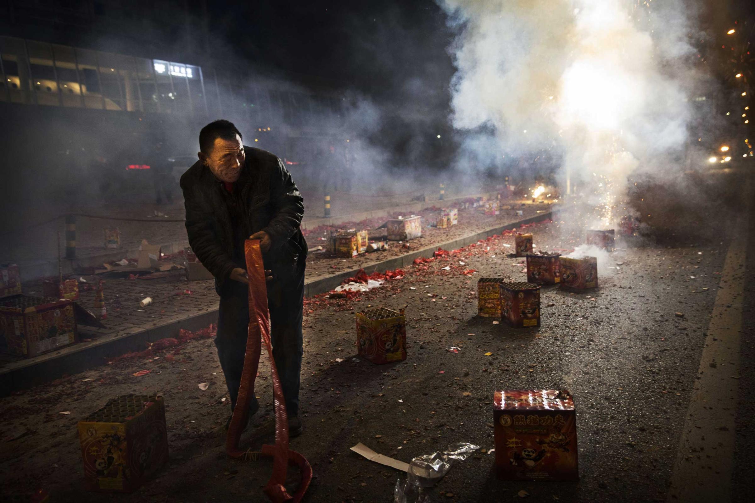 A Chinese man reacts as firecrackers he lit explode during celebrations of the Lunar New early on Feb. 19, 2015 in Beijing.