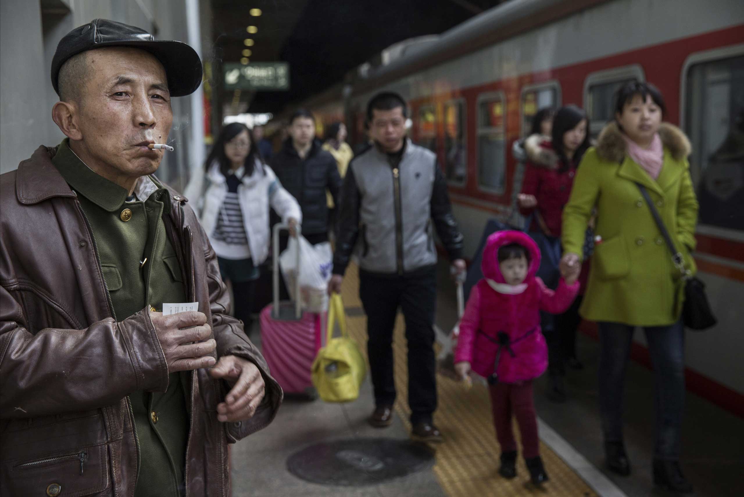 A traveler smokes as he and others prepare to board a train while leaving for the Spring Festival at a local railway station on Feb. 17, 2015 in Beijing.