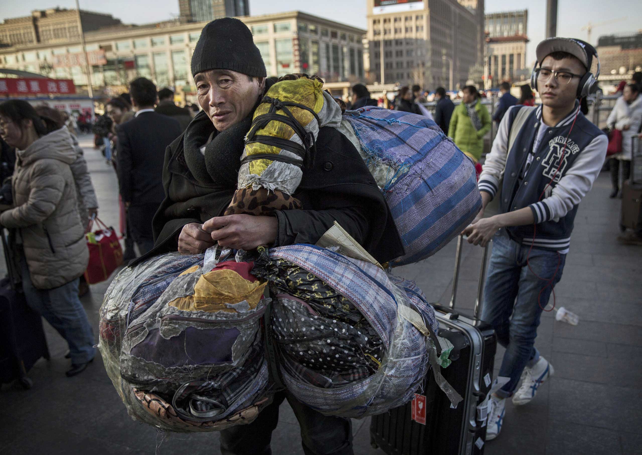 Men wait in line with their belongings as they enter a railway station during the Spring Festival on Feb. 17, 2015 in Beijing.