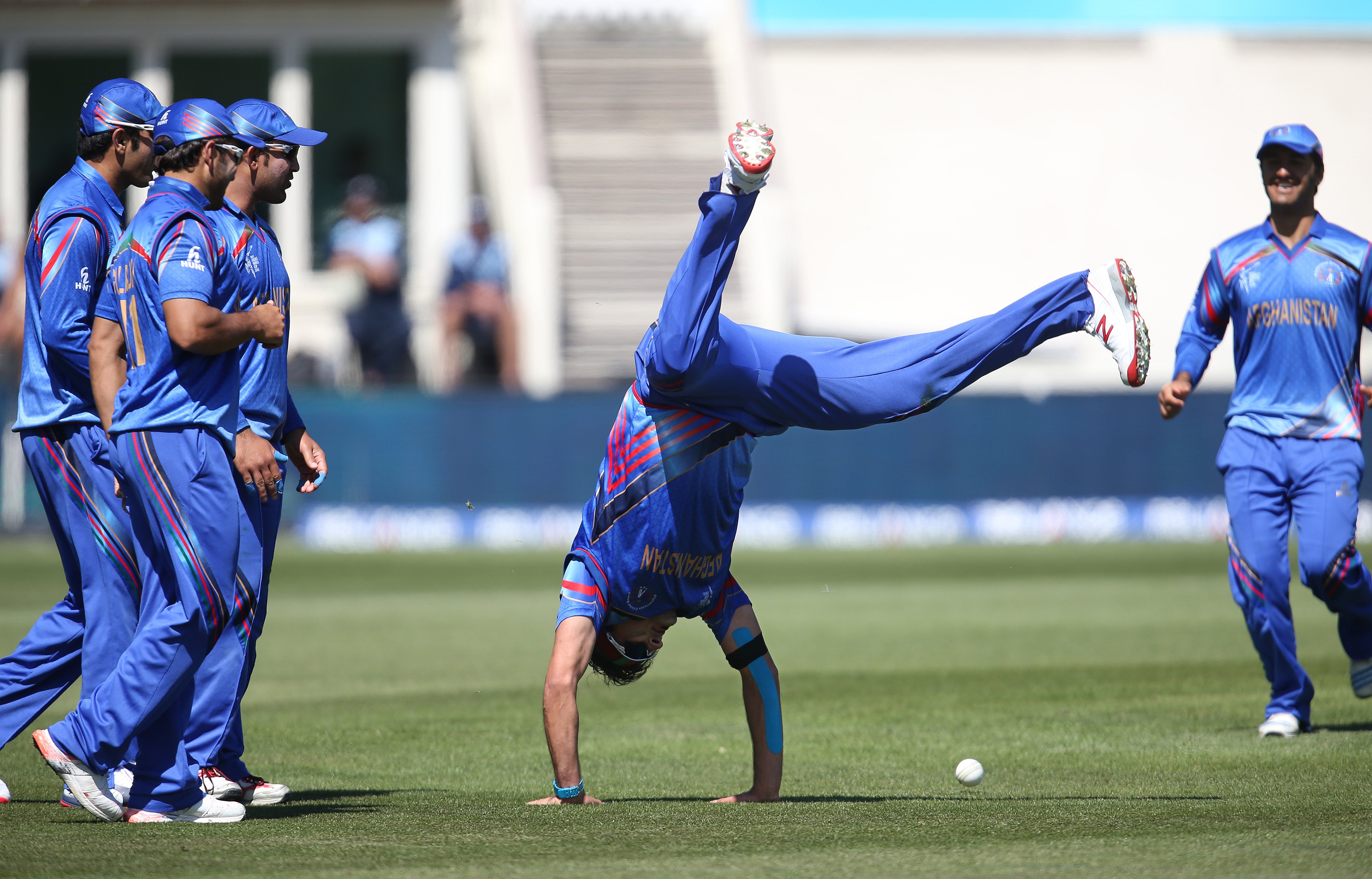 Afghanistan's Hamid Hassan is watched by his teammates as he performs a hand-stand after taking a catch to dismiss Scotland's Josh Davey during their Cricket World Cup Pool A match in Dunedin, New Zealand, Thursday, Feb. 26, 2015. (Dianne Manson—AP)