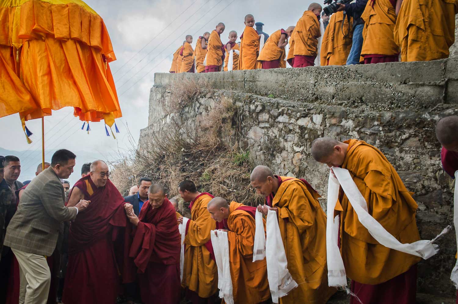 Tibetan Buddhist monks holding ceremonial scarfs stand in a line to welcome their spiritual leader the Dalai Lama, as he arrives at the Jhonang Takten Phuntsok Choeling monastery in Shimla, India, March 2014.
