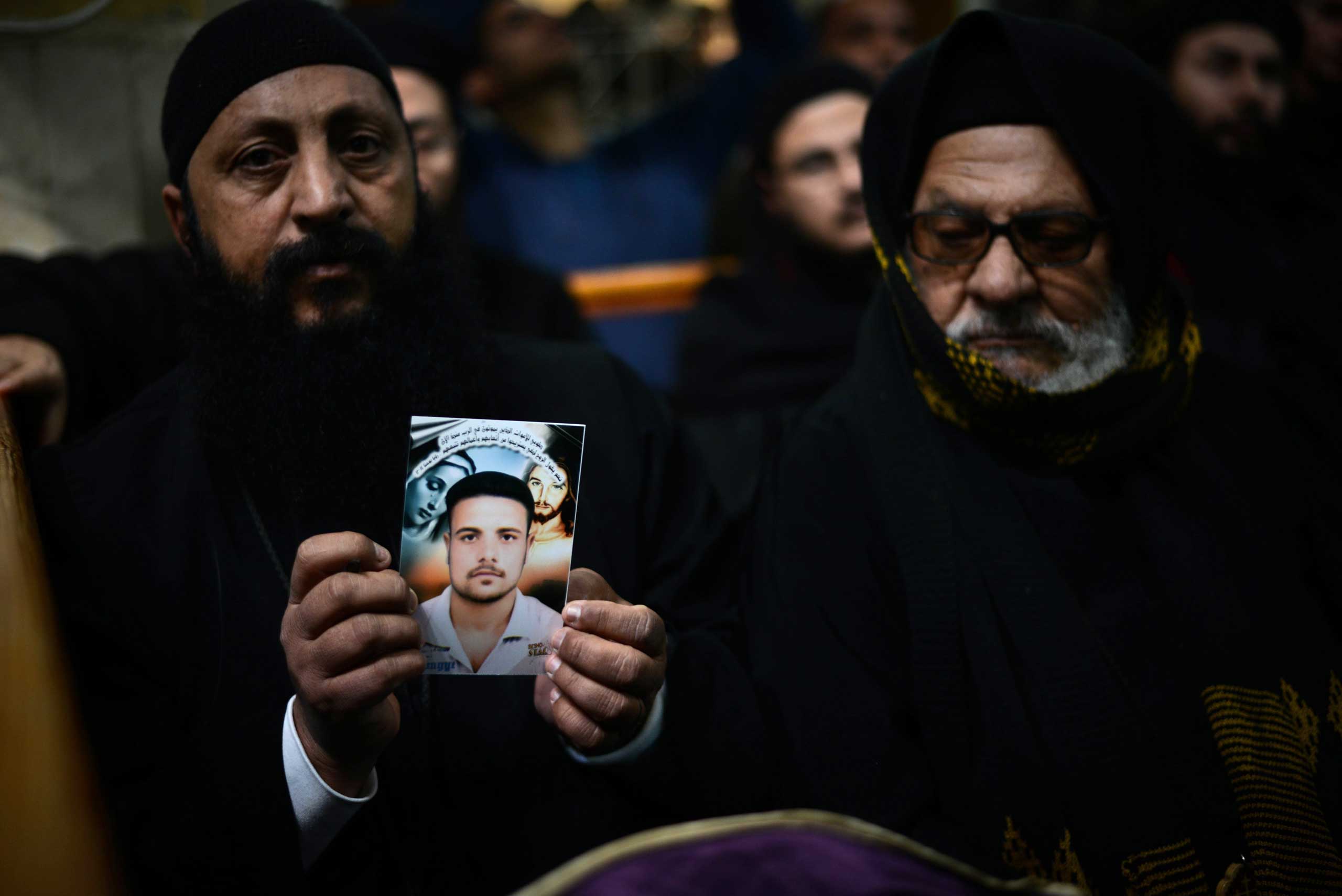 A Coptic clergyman shows a picture of a man whom he says is one of the Egyptian Coptic Christians purportedly killed by ISIS militants in Libya, on Feb. 16, 2015, during a memorial ceremony in the village of Al-Our in Egypt's southern province of Minya.
