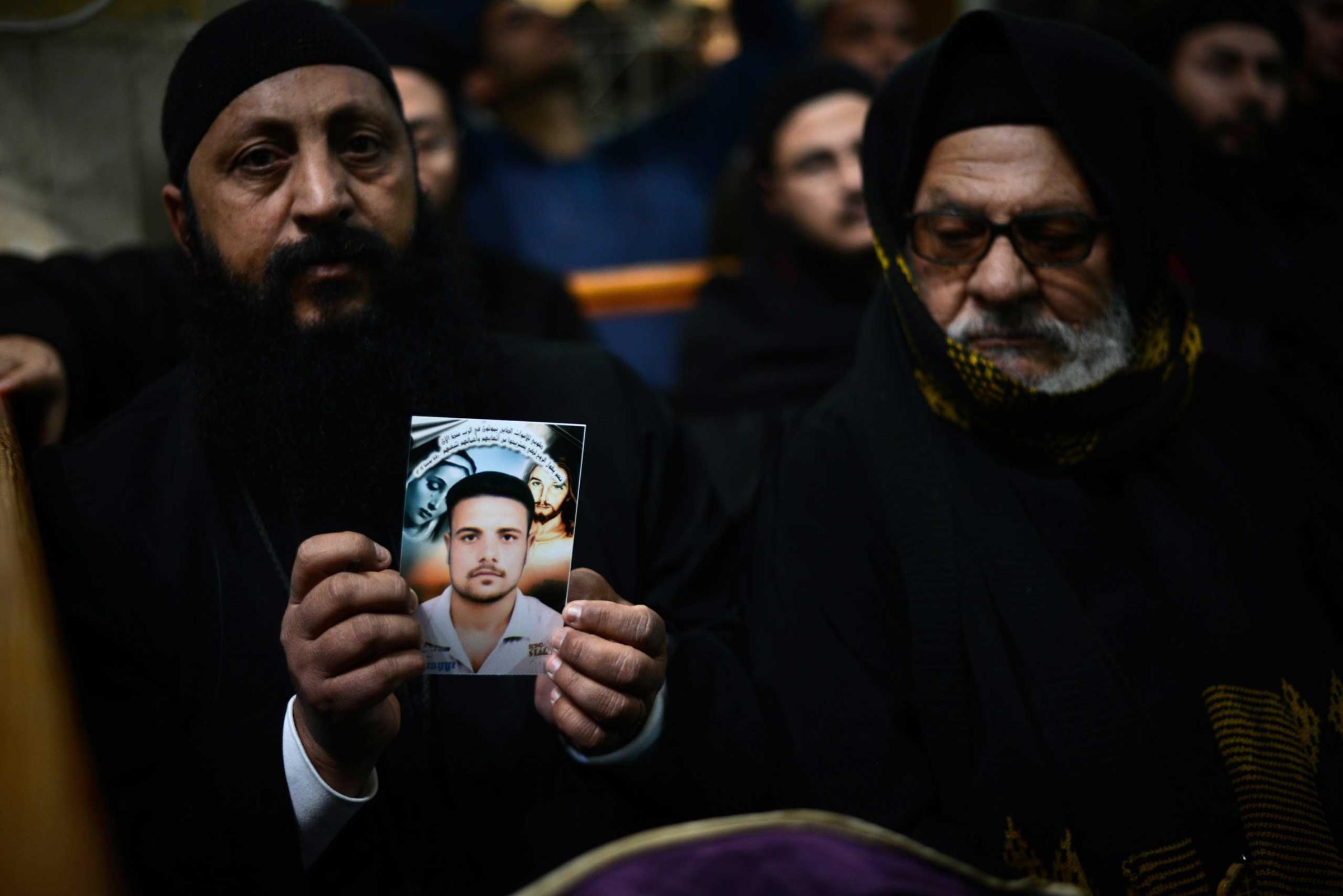A Coptic clergyman shows a picture of a man whom he says is one of the Egyptian Coptic Christians purportedly murdered by ISIS group militants in Libya, on Feb. 16, 2015, during a memorial ceremony in the village of al-Awar in Egypt's southern province of Minya.