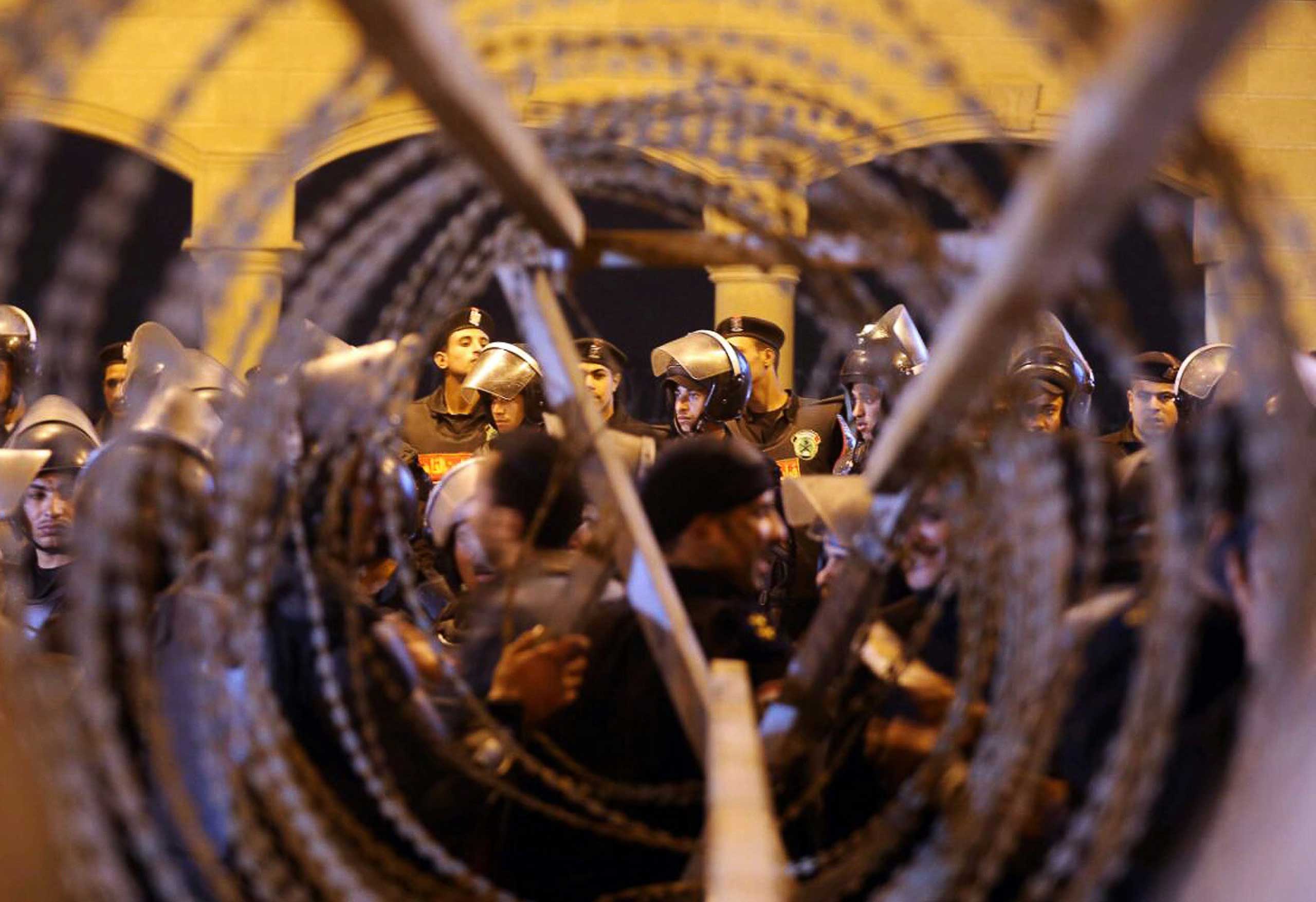 Policemen and soccer fans are seen through barbed wire as fans attempt to enter a stadium to watch a match, on the outskirts of Cairo, Feb. 8, 2015. (Al Youm Al Saabi—Reuters)