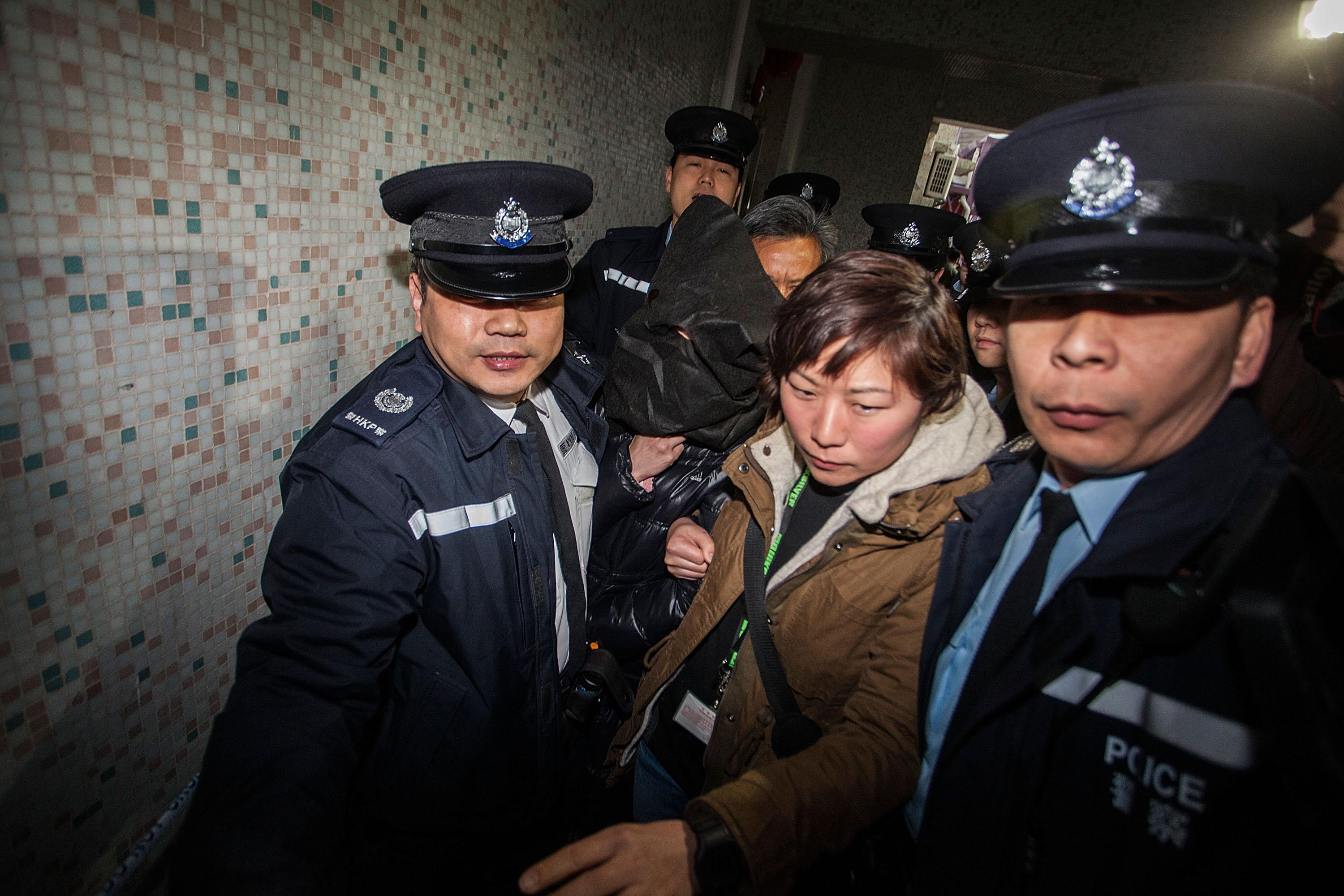 Police escort Law Wan-tung to her home for further investigation on Jan. 21, 2014, in Hong Kong (Lam Yik Fei—Getty Images)