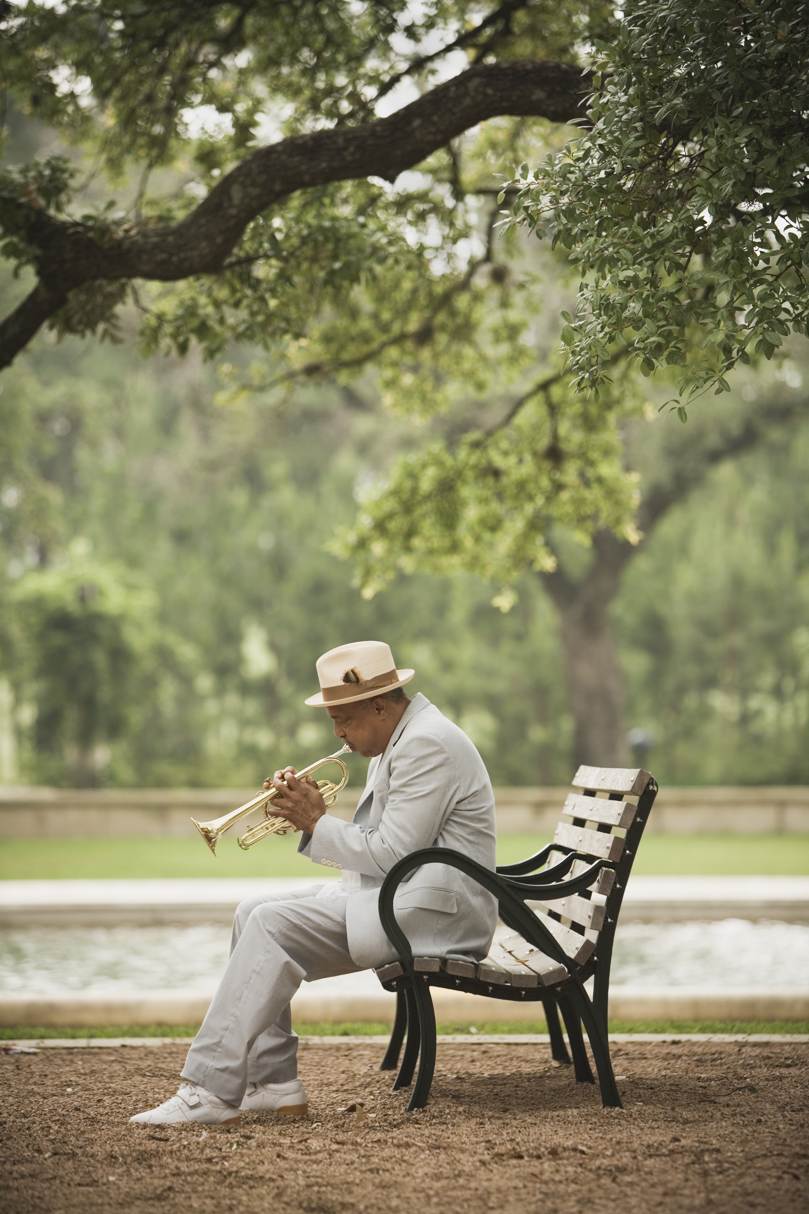 man-playing-trumpet-park-bench