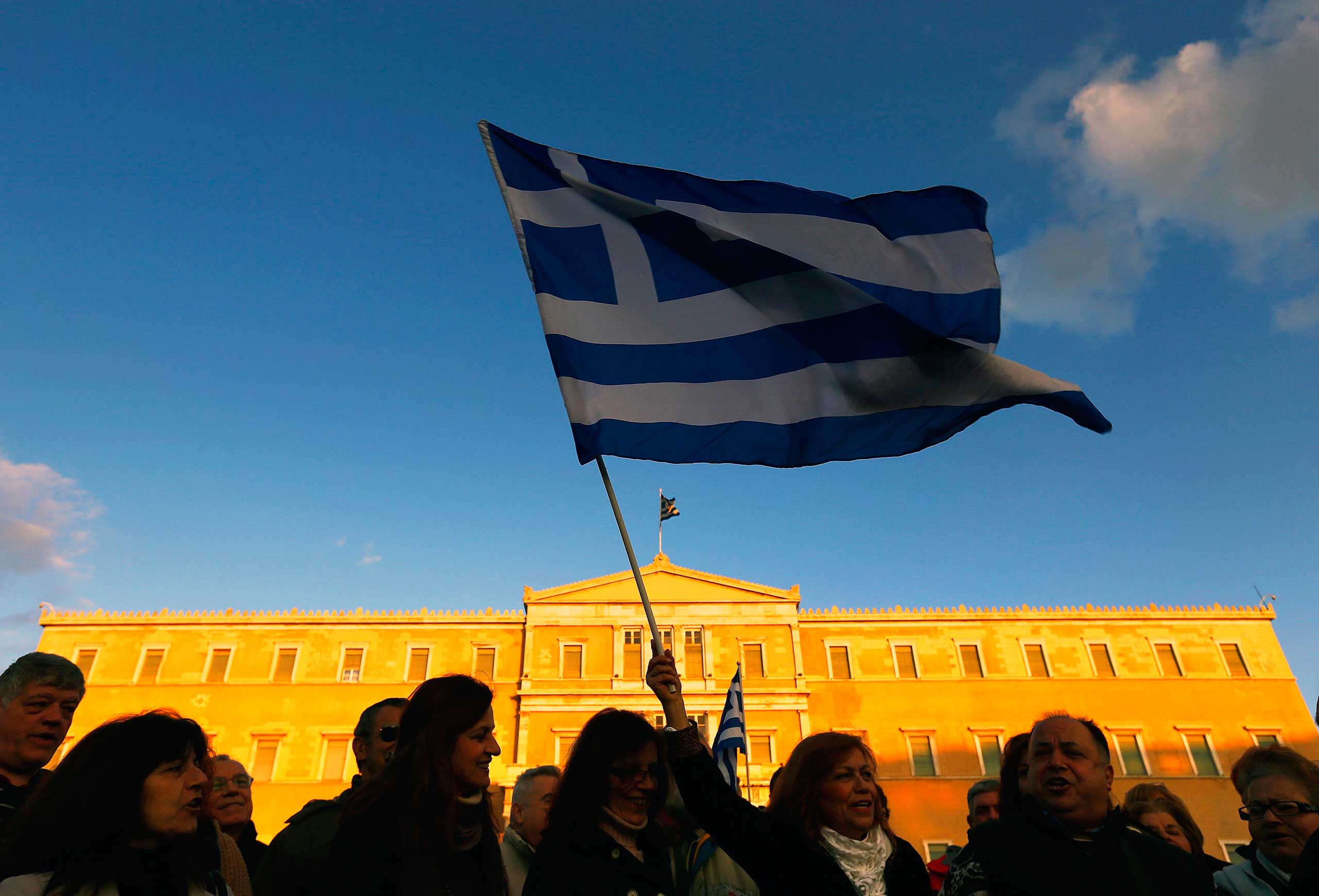People wave Greek flags in front of the parliament during anti-austerity pro-government demonstration in Athens