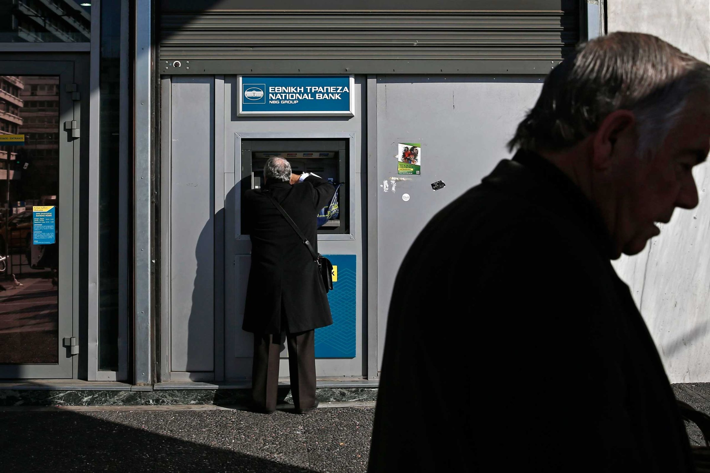 A man makes a transaction at an ATM outside a National Bank of Greece branch in Athens, Feb. 19, 2015.