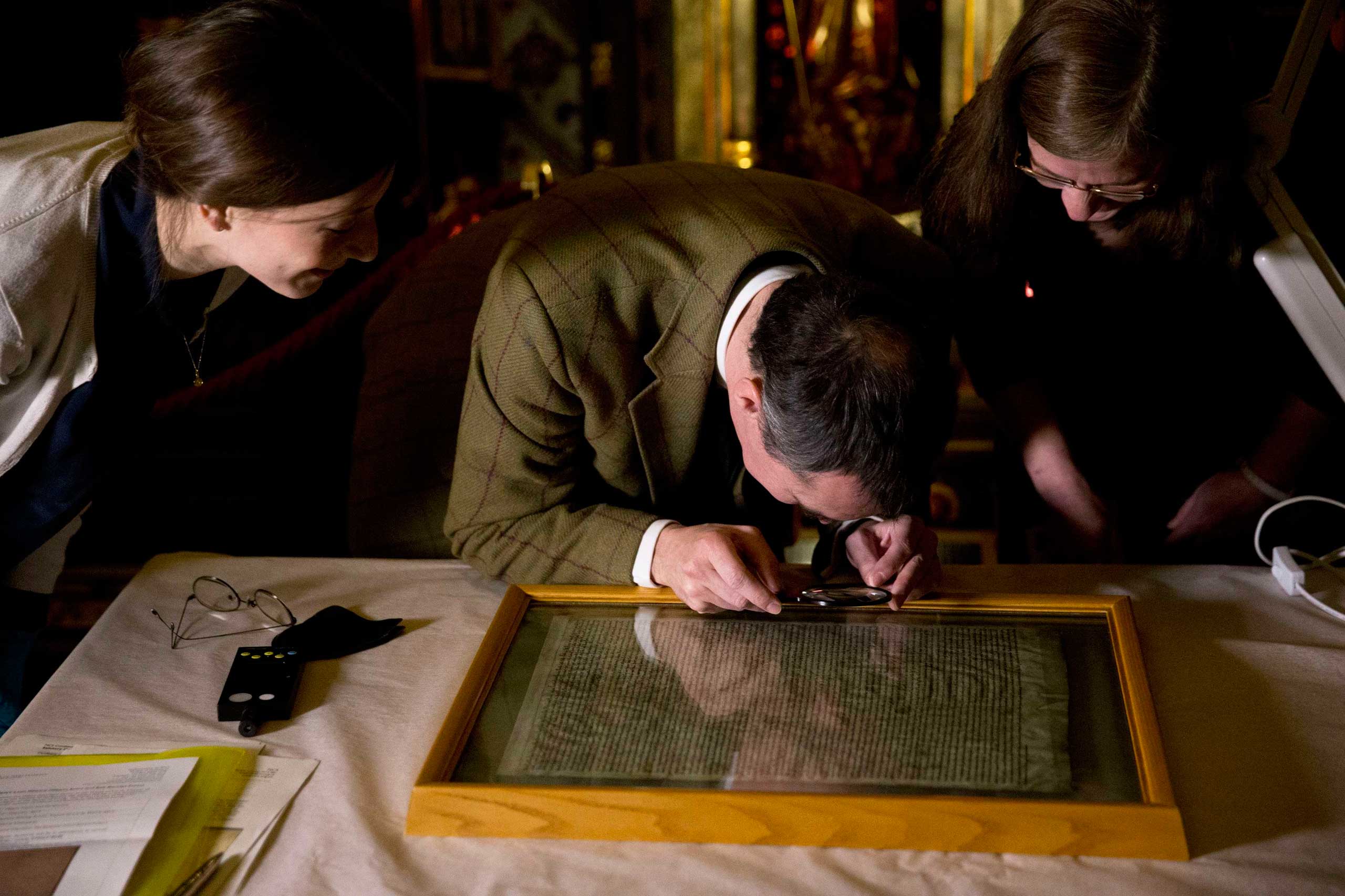 The Salisbury Cathedral copy of the Magna Carta is viewed by archivists before being displayed alongside the other three surviving original parchment engrossments of the Magna Carta, as they are displayed to mark the 800th anniversary of the sealing of the Magna Carta in 1215, in the Queen's Robing Room at the Houses of Parliament in London on Feb. 5, 2015. (Matt Dunham—Pool/Reuters)