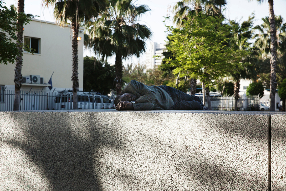 A man sleeping in Levinsky Park next to the Central bus station. When refugees are released into Israeli society they are given a bus ticket to this bus station in Tel Aviv. Not knowing where to go, some refugees sleep in the park until they find housing, and it has become a central point for the African community.