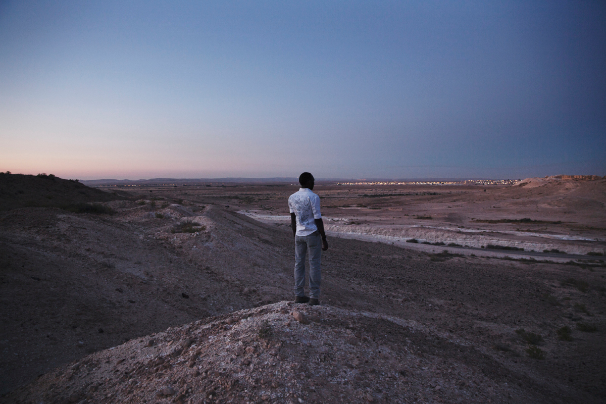 Nouraldin, 26 years old, Overlooking the Negev desert and Holot Detention Centre. He has been in Israel for 6 years. He has been in Holot since March 9th. He is a refugee from Sudan, Darfur. “Yesterday was the first time I ever lied to my mother. She asked me where I was, and I told her I was in Tel Aviv and everything is fine. She asked me why I was lying because she saw on the news in Sudan that they were putting Sudanese people in a prison. I have never lied to her before and I felt really bad about it.”