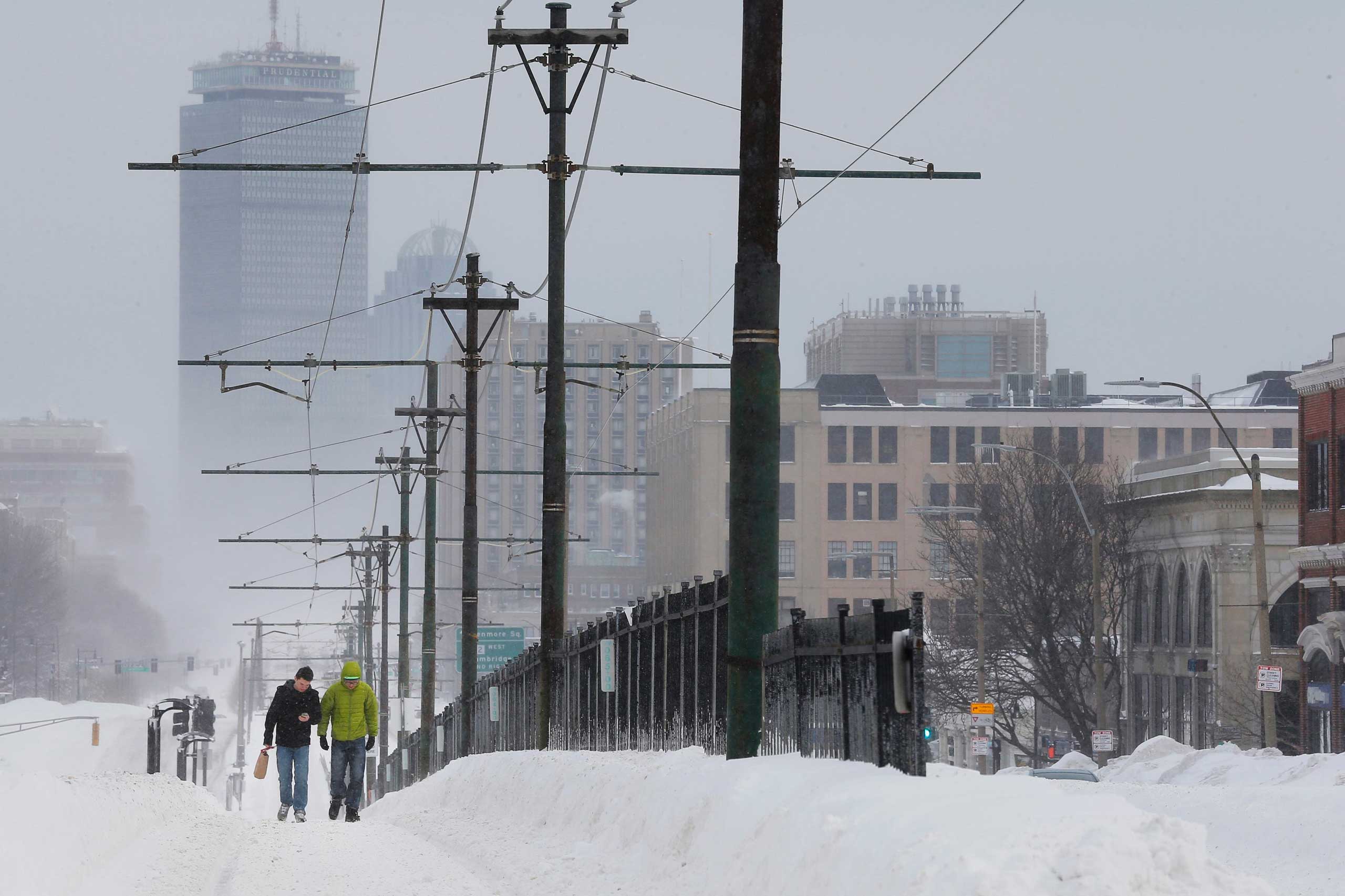 Pedestrians walk along snow covered, MBTA subway rails on Commonwealth Avenue in Boston