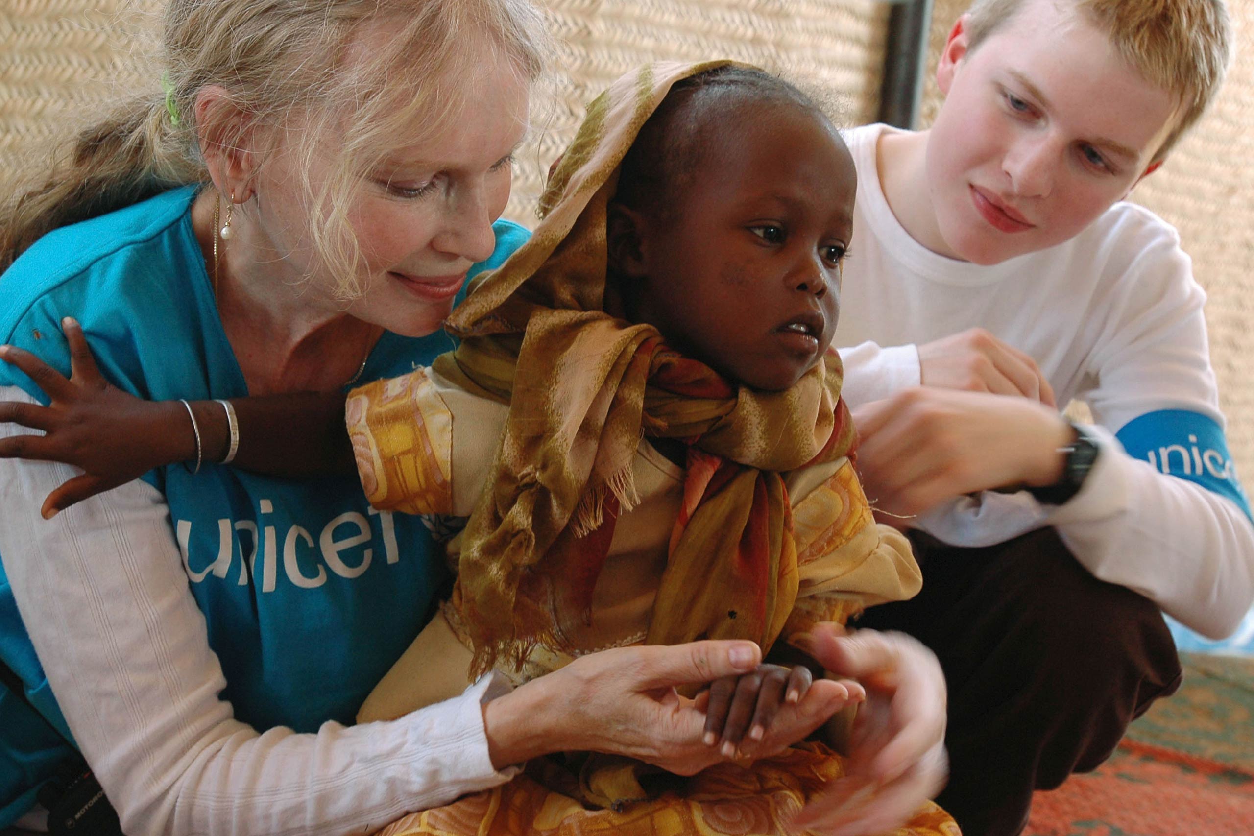 Mia Farrow, a UNICEF goodwill ambassador, and her son Seamus hold a Sudanese child in the internally displaced people camp of Abu Shouk near Al Fasher city on Nov. 7, 2004 in Darfur, Sudan.