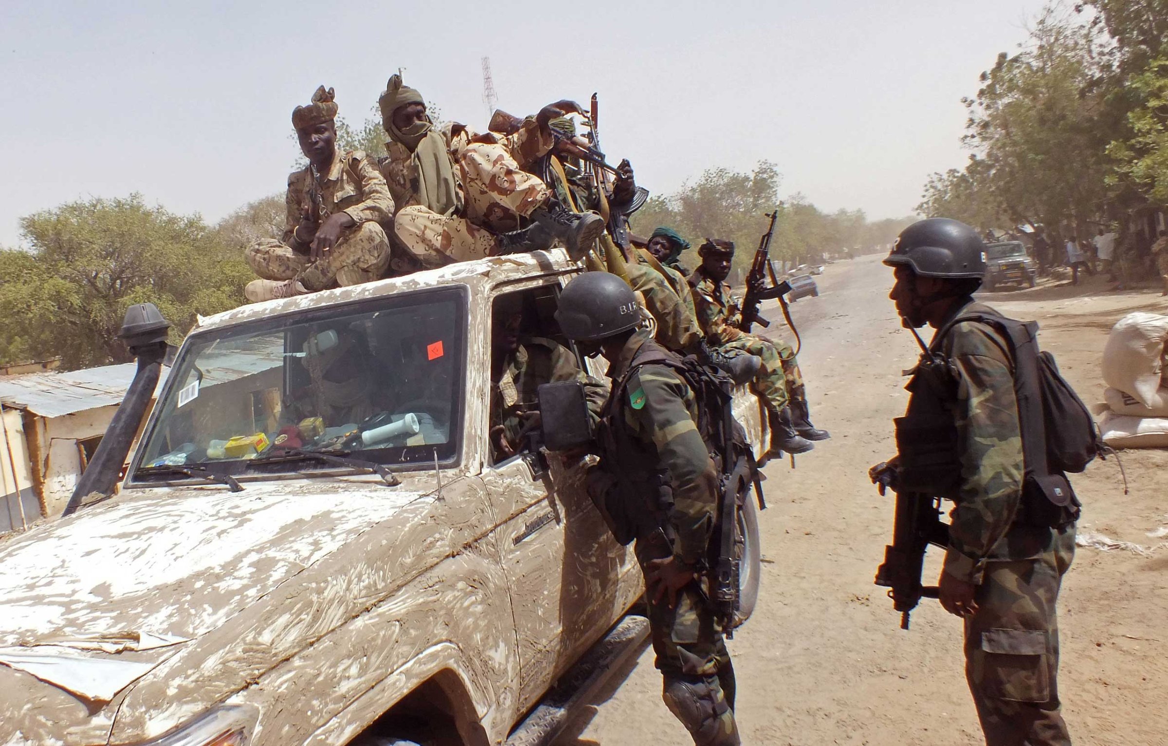 Chadian soldiers on top of a truck, left, speak to Cameroon soldiers, right, standing next to the truck, on the border between Cameroon and Nigeria as they form part of the force to combat regional Islamic extremists force's including Boko Haram, near the town of Gambarou, Nigeria, Feb. 19, 2015.