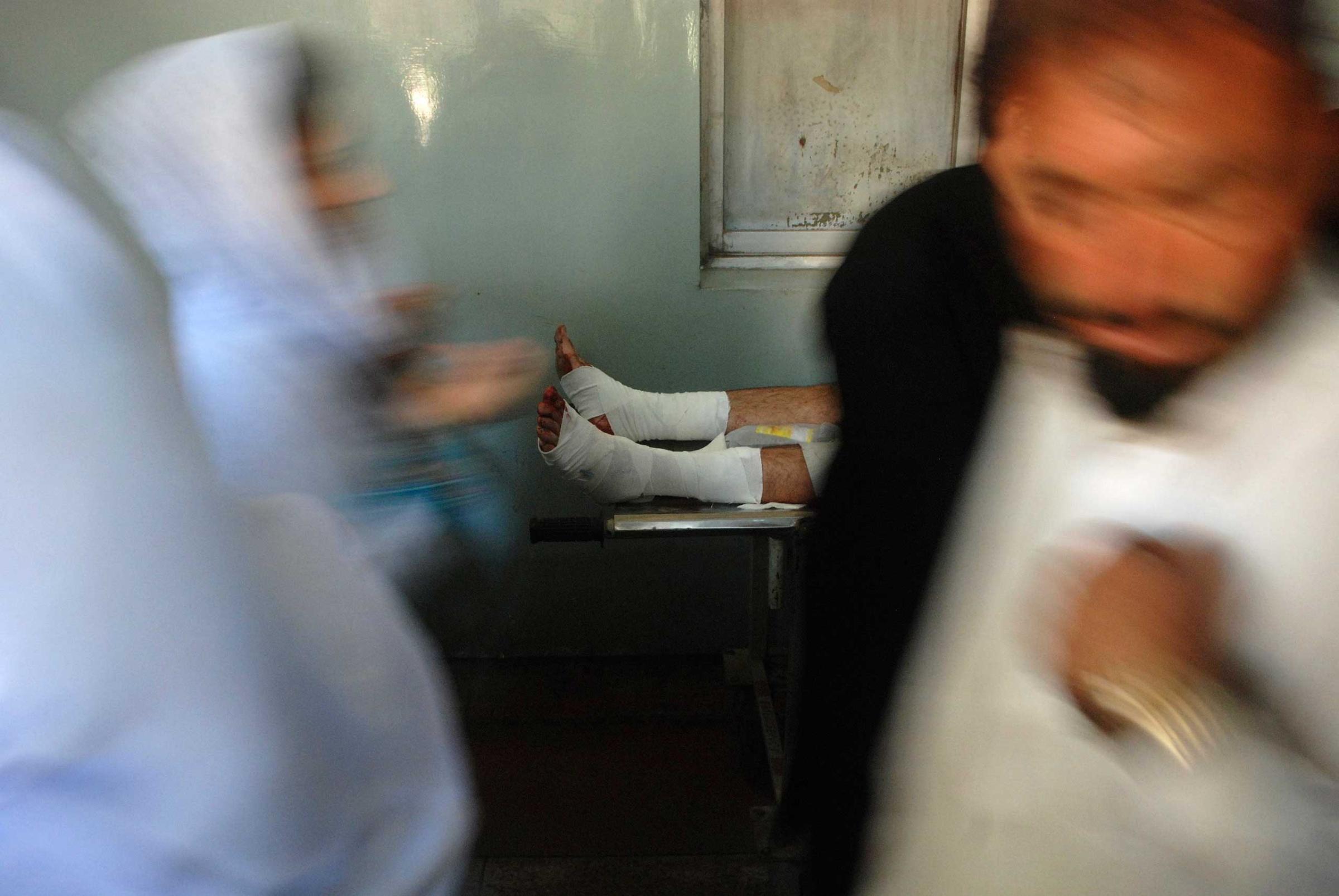 People move past a man, who was wounded in an explosion in a Shi'ite mosque, as he lies on a stretcher at a hospital in Peshawar Feb. 13, 2015.