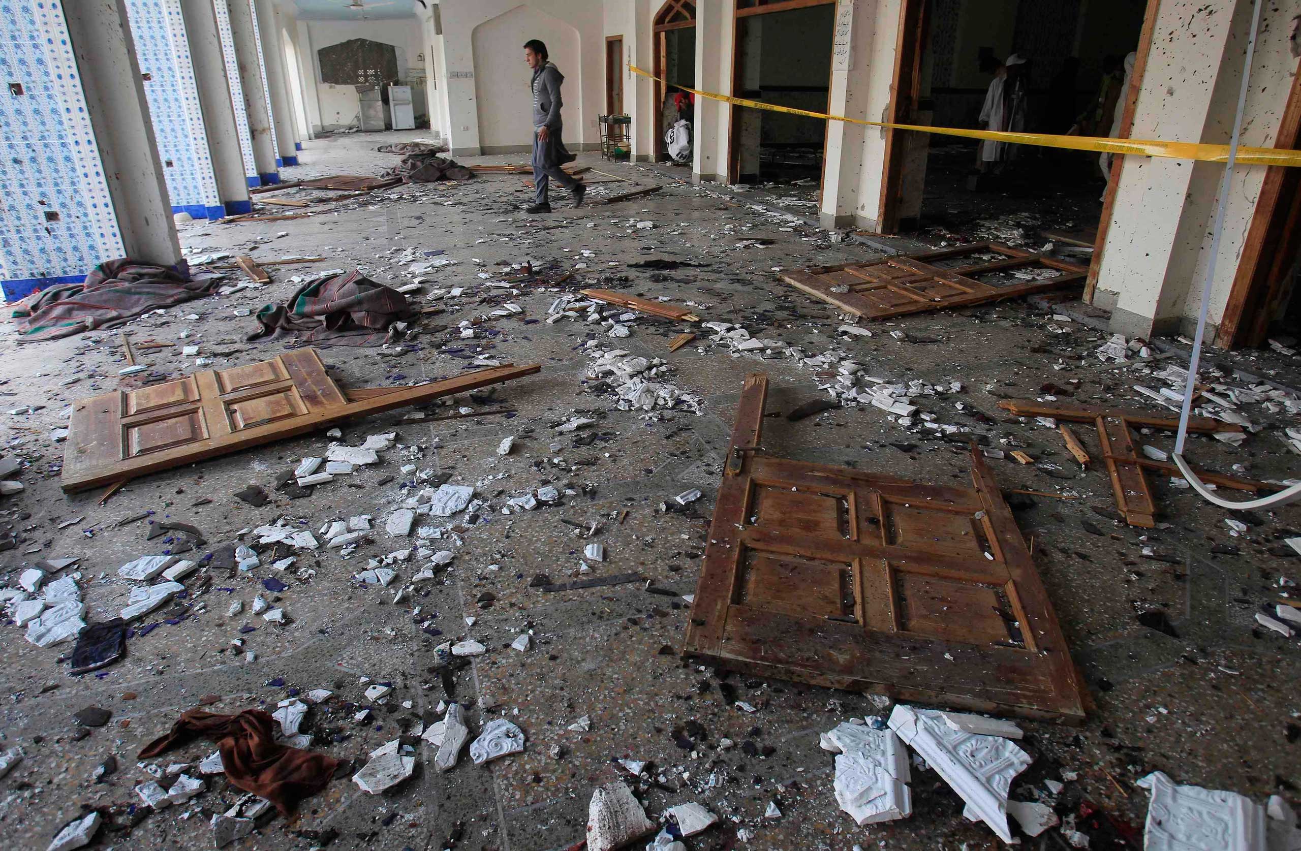 A man walks past broken glass and doors after an explosion in a Shi'ite mosque in Peshawar Feb. 13, 2015.