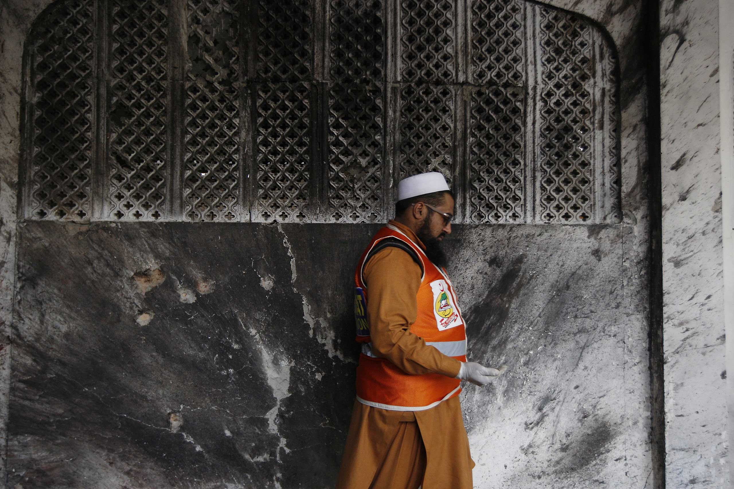 A Pakistani official collects forensic evidence at a Shi'ite mosque attacked by suicide bombers and gunmen in Peshawar, Feb. 13, 2015.