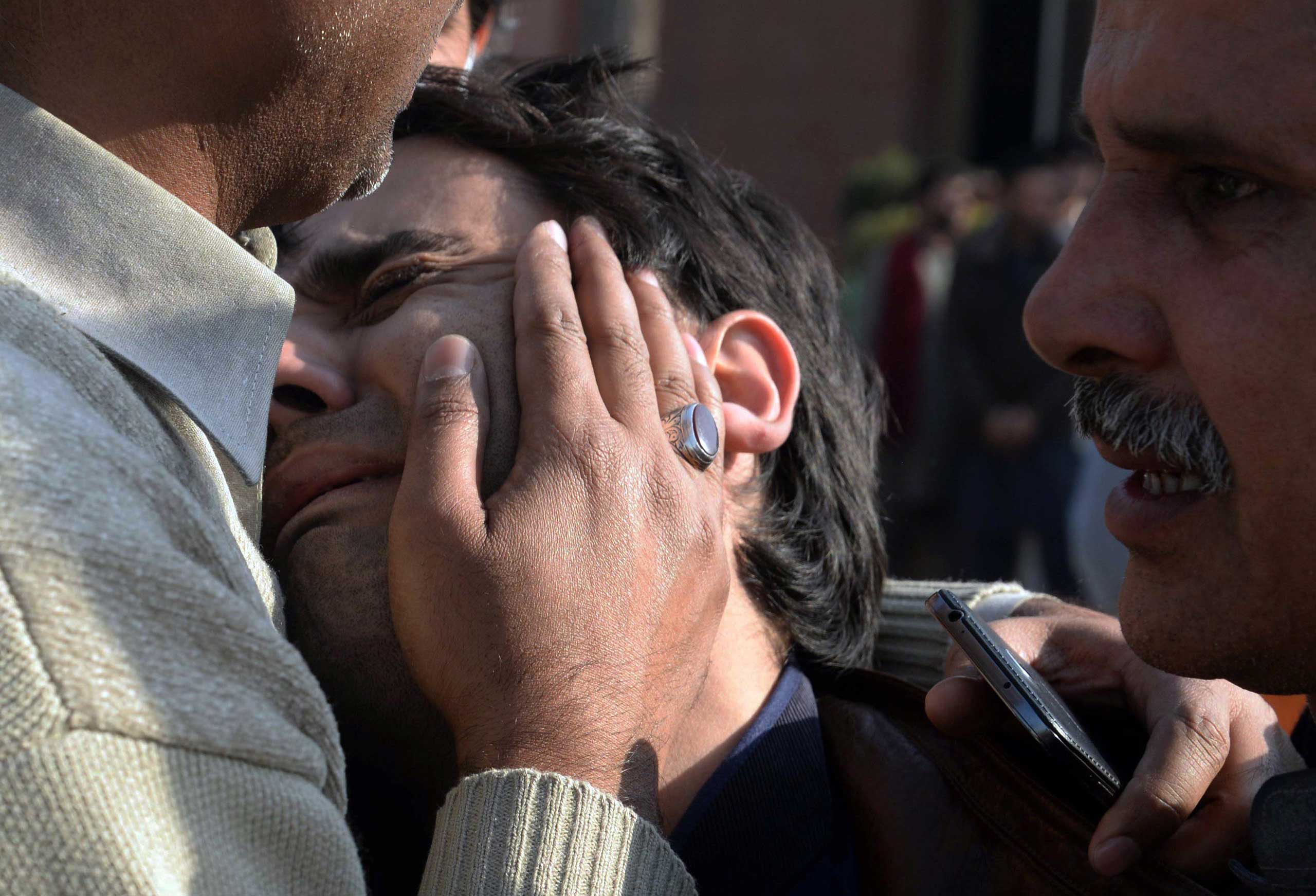 Pakistani relatives comfort a resident following an attack by Taliban militants on a Shi'ite Muslim mosque in Peshawar on Feb. 13, 2015.