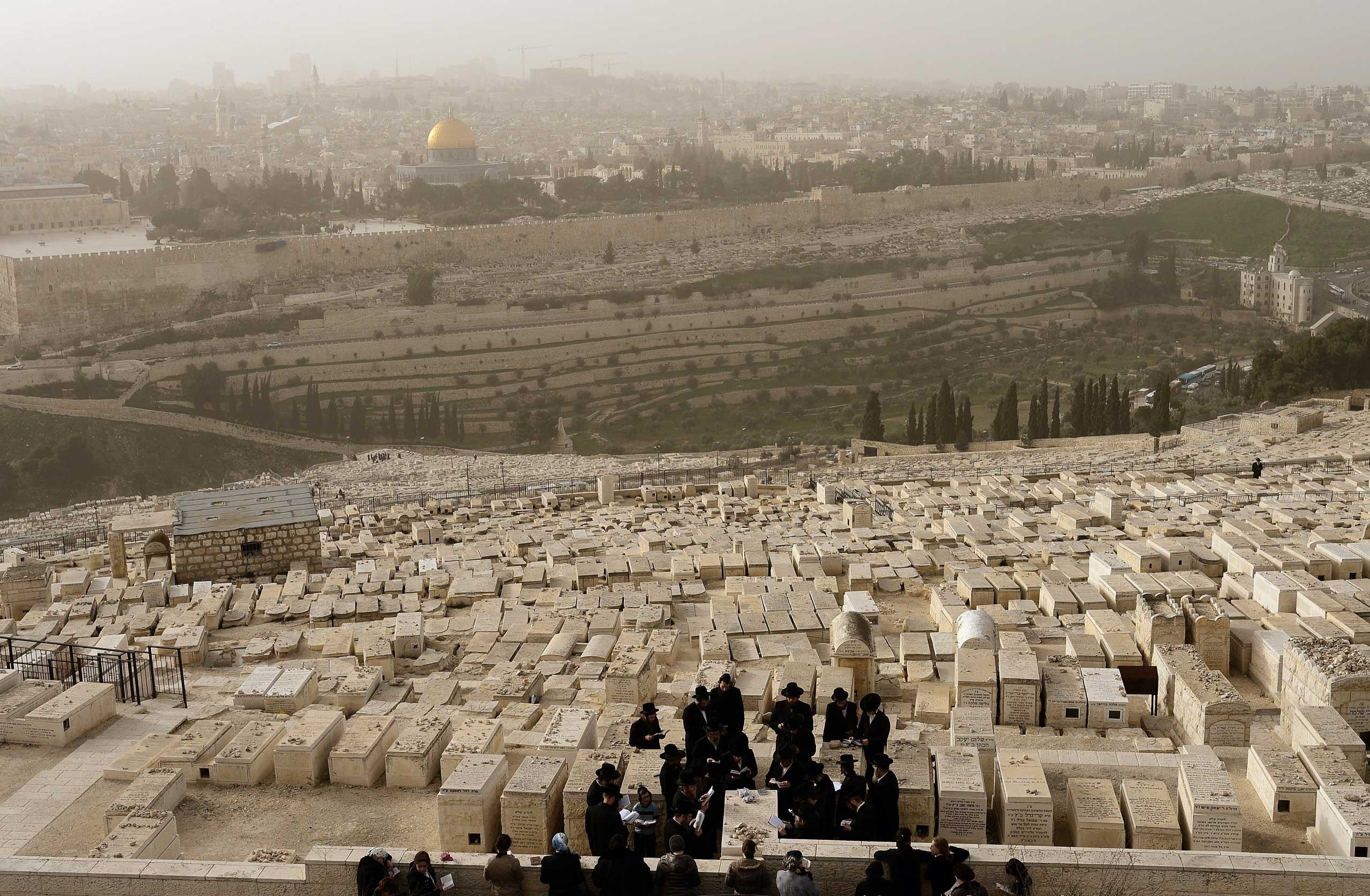 Feb. 10, 2015. A group of Ultra-orthodox Jewish men pray for their deceased relatives at the Jewish cemetery on the Mount of Olives in Jerusalem.