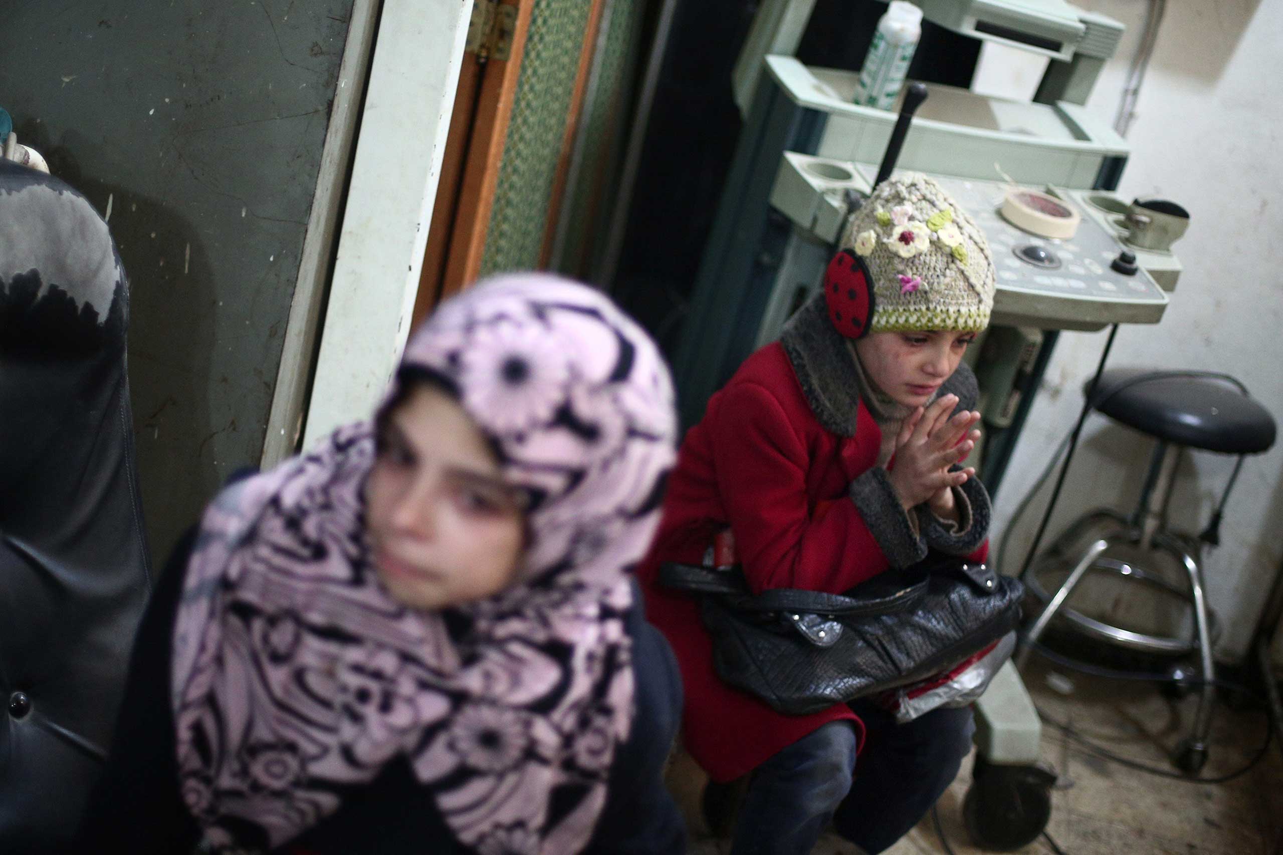 Feb. 9, 2015. Syrian girls react as they sit at a clinic in the rebel-held area of Douma, east of the capital Damascus, following reported air strikes by regime forces. Tens of thousand residents trapped in the rebel bastion suffer from food and medical shortages, as well as deadly regime bombardment.