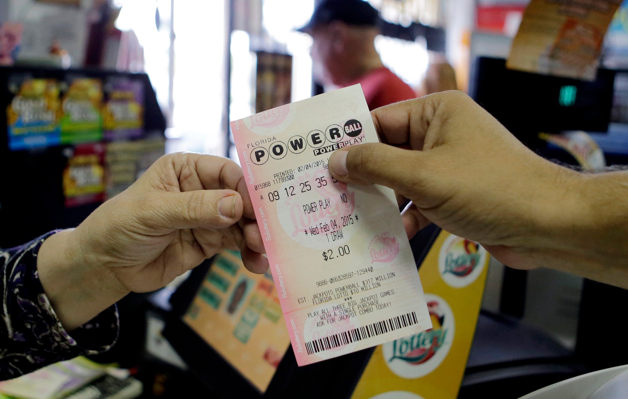 A store clerk hands a customer his Powerball ticket at a local grocery store in Hialeah, Fla., Wednesday, Feb. 4, 2015