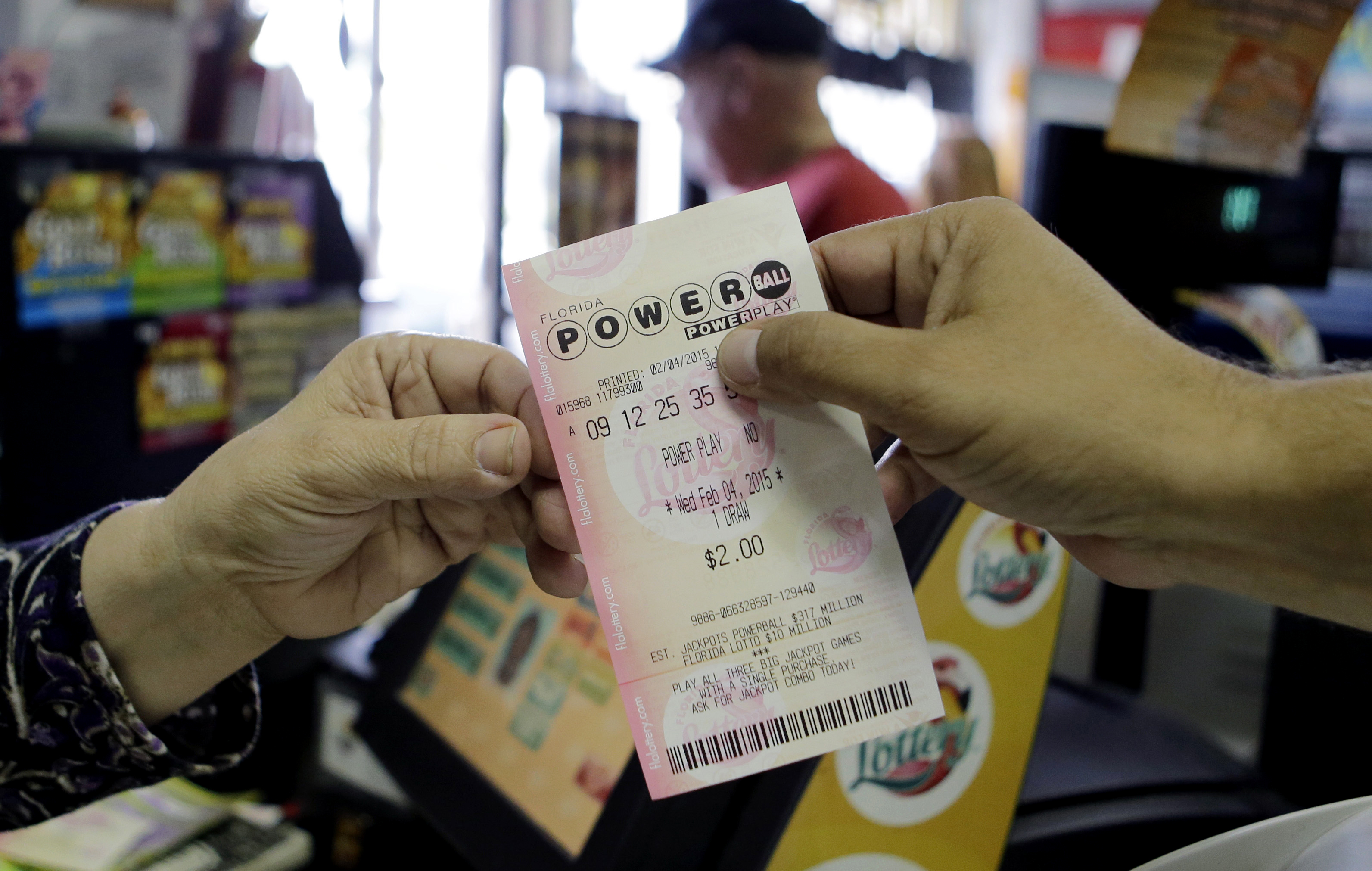 A store clerk hands a customer his Powerball ticket at a local grocery store in Hialeah, Fla., Wednesday, Feb. 4, 2015 (Alan Diaz—AP)