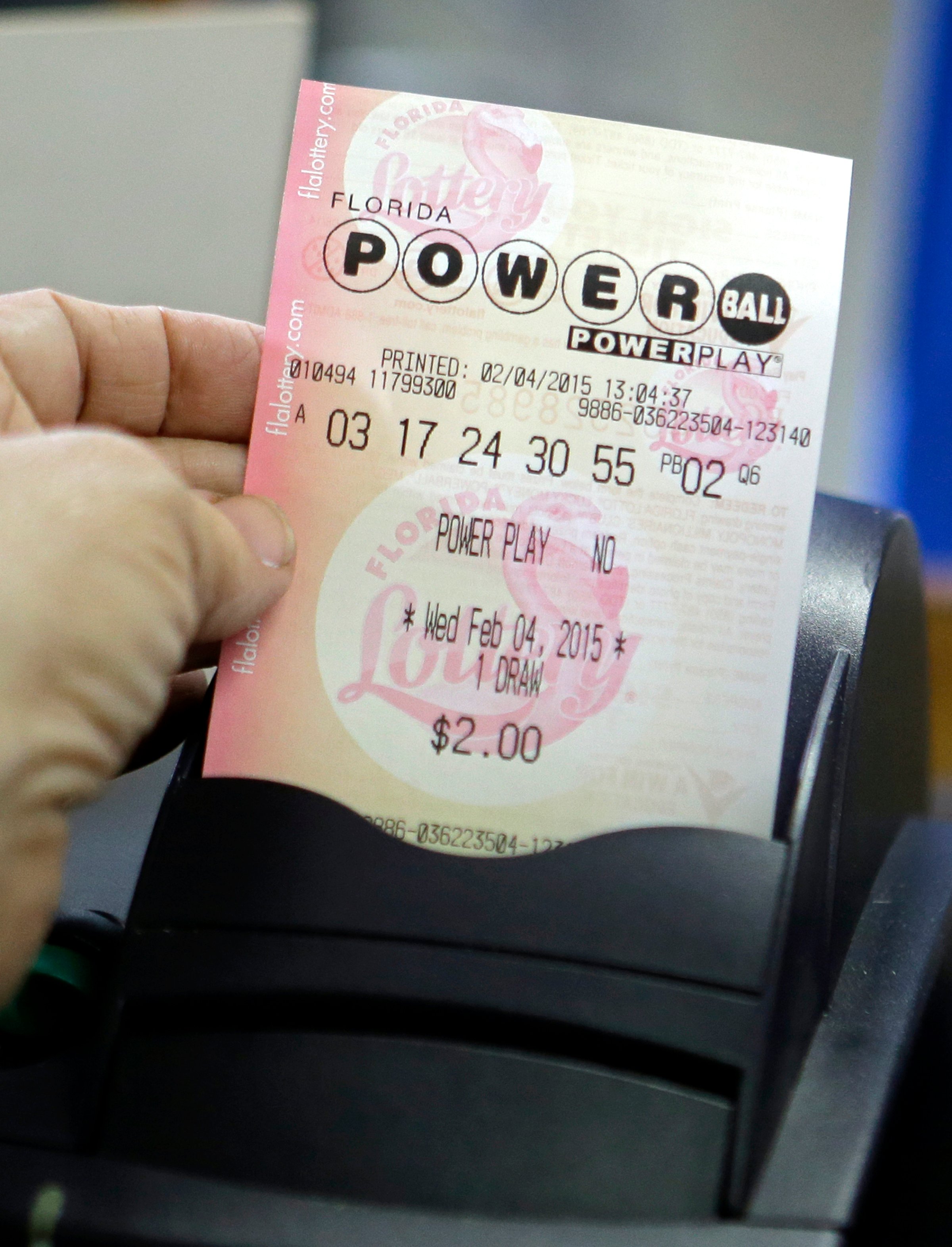 A store clerk pulls a Powerball ticket after being printed for a customer at a local grocery store in Hialeah, Fla. on Feb. 4, 2015.