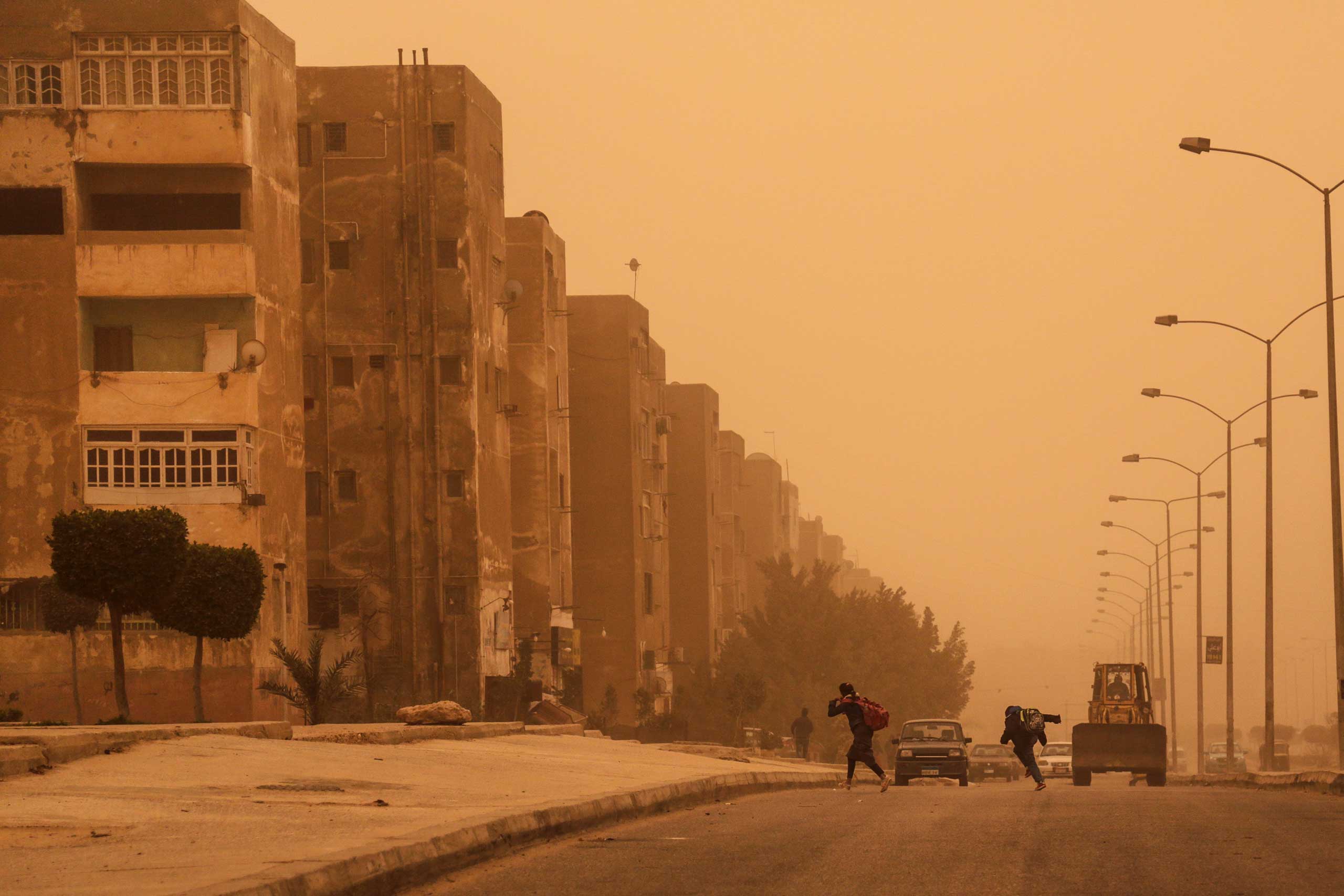 Young students run to their homes during a sandstorm in 6 October city, a suburb southwest of Cairo, Feb. 11, 2015.