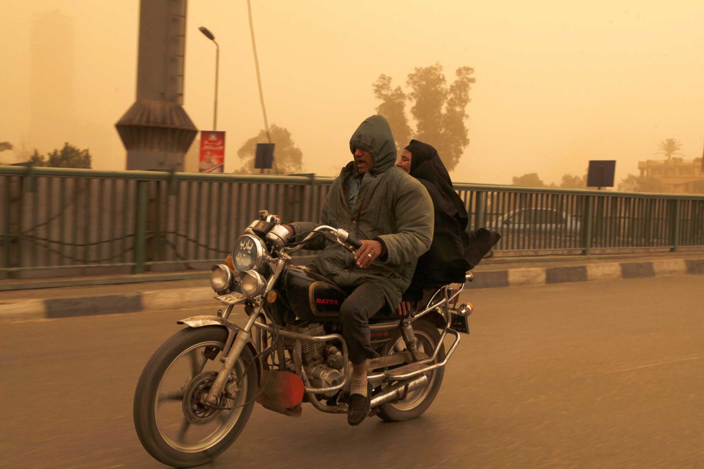 A man and a woman ride on a motorcycle over a bridge during a sand storm in Cairo, Feb. 11, 2015.
