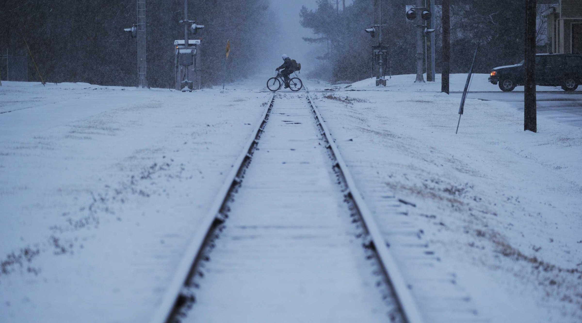 A man rides his bicycle across the railroad tracks in Exmore, Va. as snow falls, Feb. 24, 2015.
