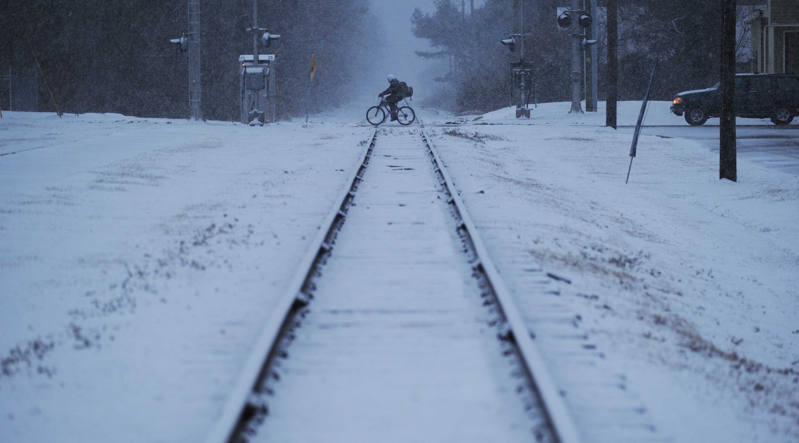 A man rides his bicycle across the railroad tracks in Exmore, Va. as snow falls, Feb. 24, 2015. (Jay Diem—AP)
