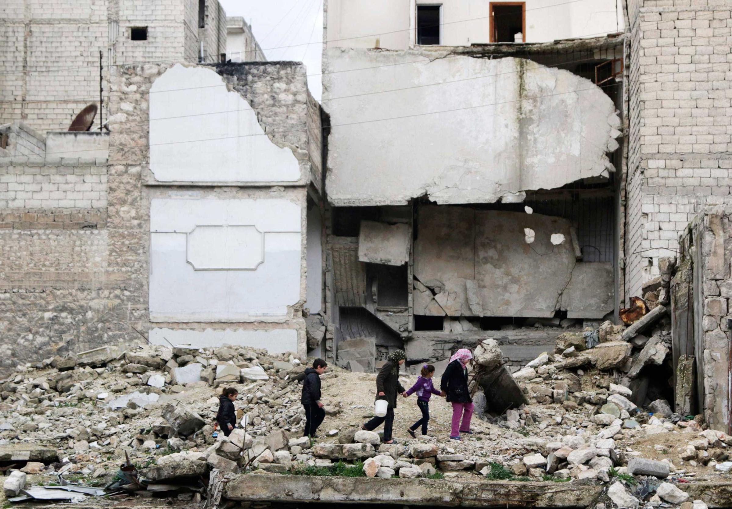 Children walk on the debris of a damaged building at al-Myassar neighborhood of Aleppo Feb. 16, 2015.