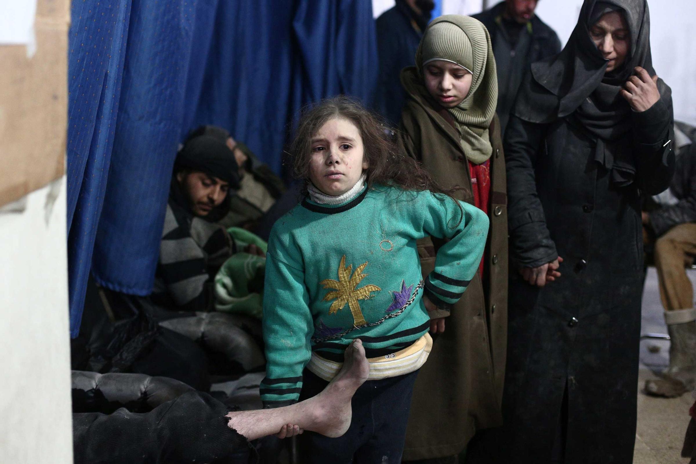 A Syrian girl holds the leg of her injured father as they wait for treatment at a clinic in in the Douma neighborhood of Damascus, following reported air strikes by regime forces on Feb. 9, 2015.