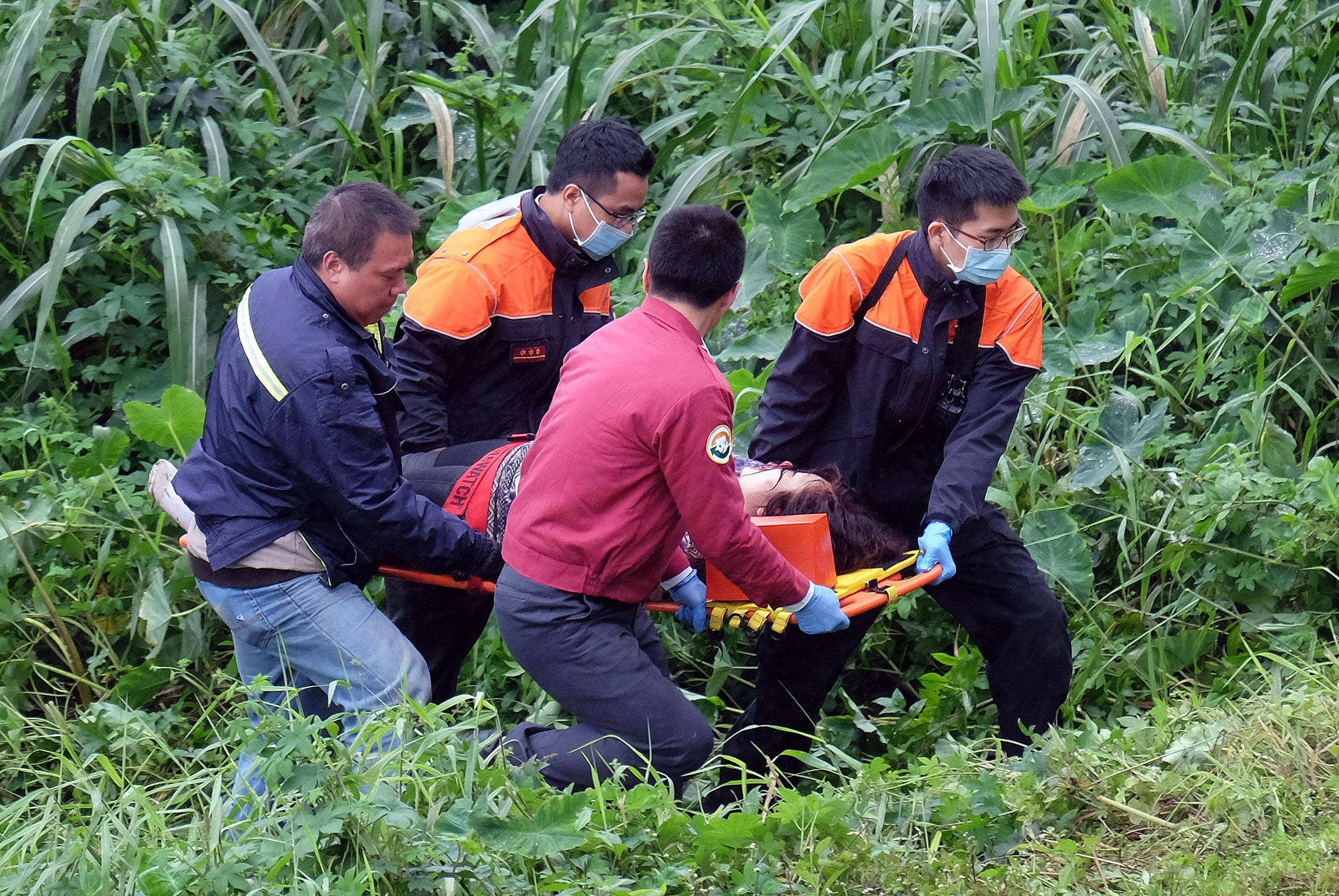 An injured passenger (C) is carried on a stretcher by emergency personnel up the river bank after a TransAsia ATR 72-600 turboprop plane crash-landed into the Keelung river outside Taiwan's capital Taipei in New Taipei City on Feb. 4, 2015.