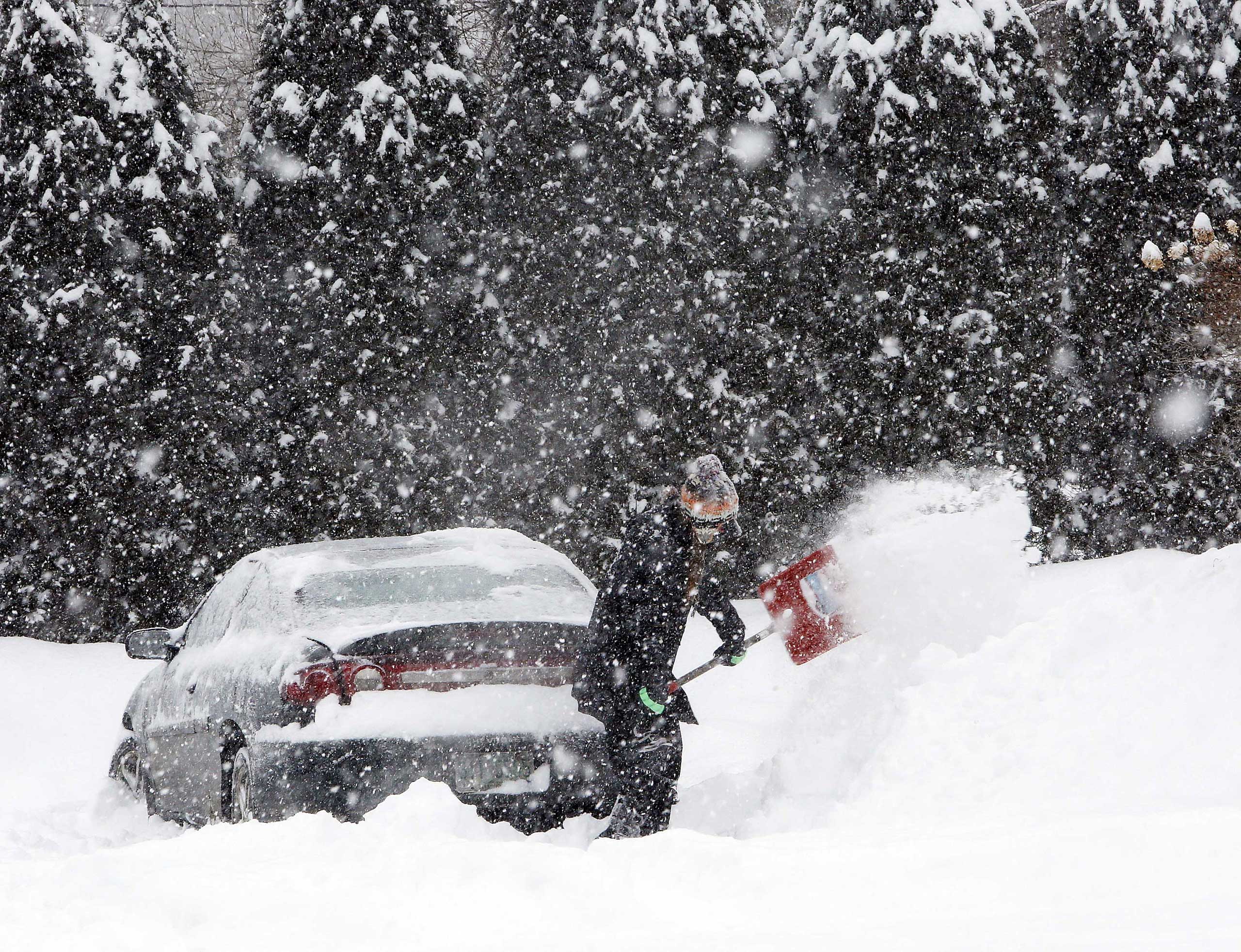 Krystal Koban removes snow from around her car during a winter storm, Monday, Feb. 2, 2015, in Henniker, N.H. (Jim Cole—AP)