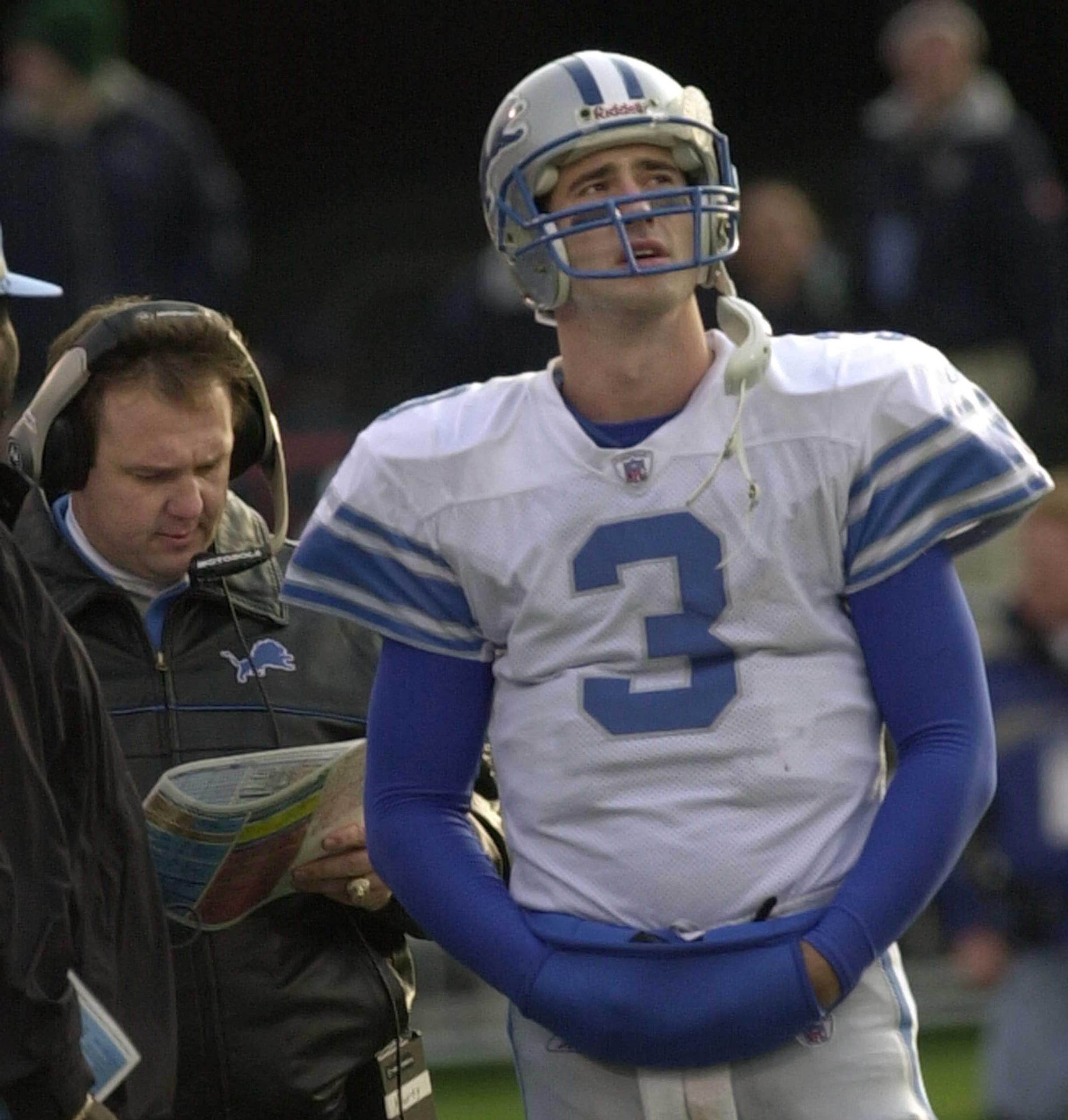 Detroit Lions quarterback Joey Harrington (3) looks at the scoreboard as coach Marty Mornhinweg looks over a playbook during the fourth quarter against the Chicago Bears in Champaign, Ill., Sunday, Nov. 24, 2002. The Bears won 20-17 in overtime. (AP Photo/Charles Rex Arbogast)