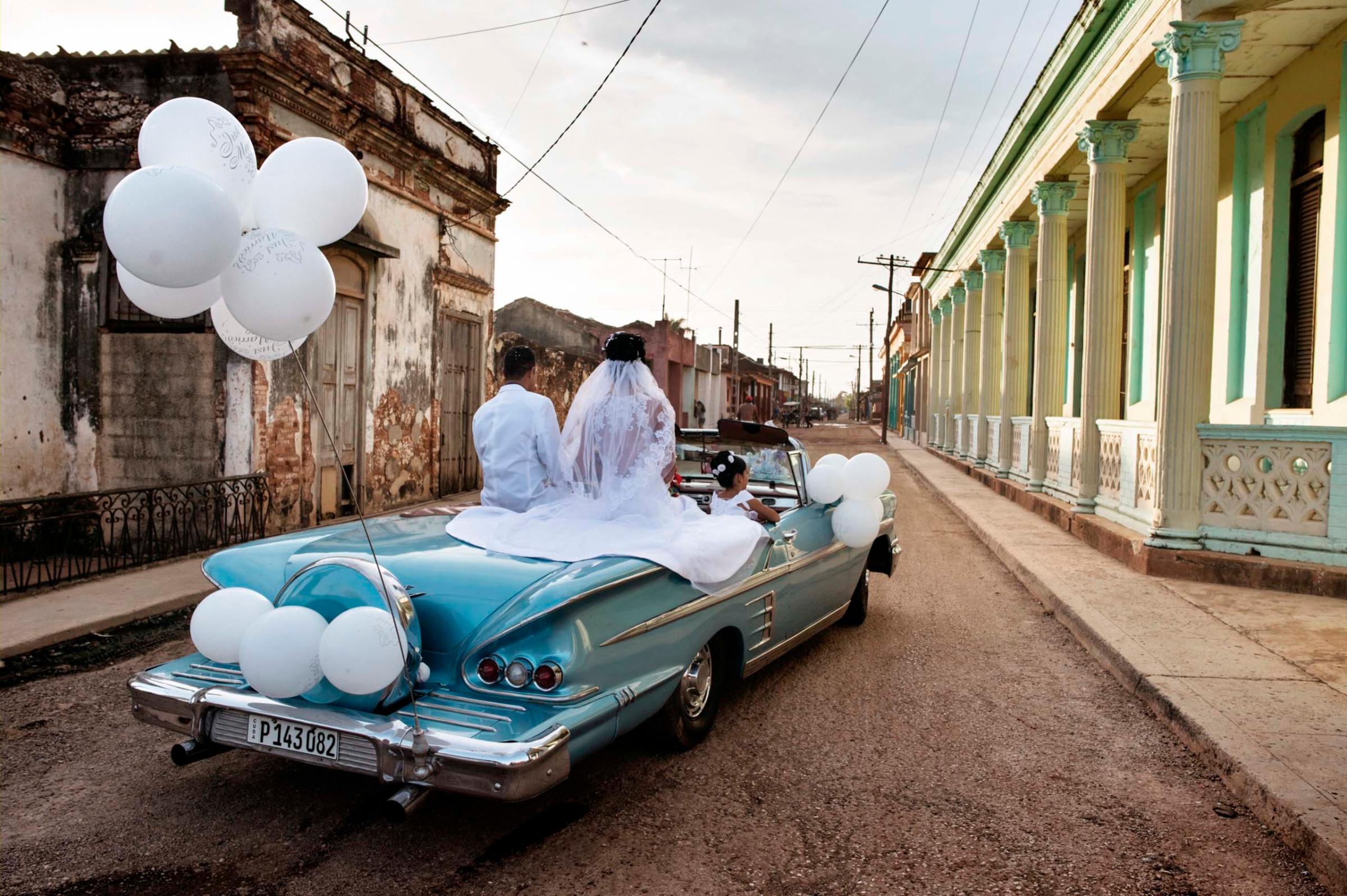 Jan. 2015. Newlyweds ride in a vintage American car through the streets of Guira de Melena. In this prosperous area outside Havana, weddings can cost as much as $20,000 dollars.