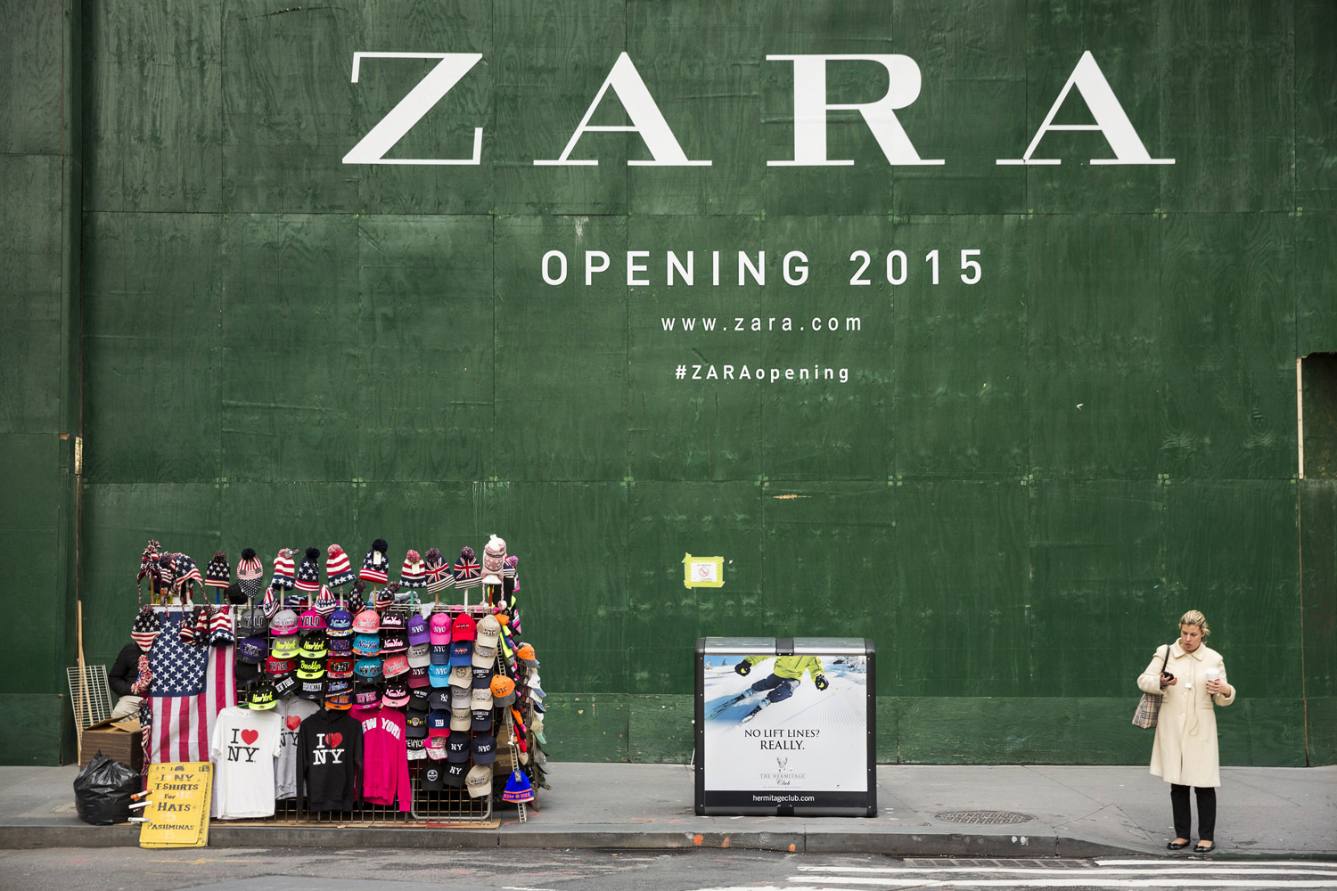 A woman checks her phone next to the construction site of a new Zara store in downtown Manhattan, New York, Dec 17, 2014.