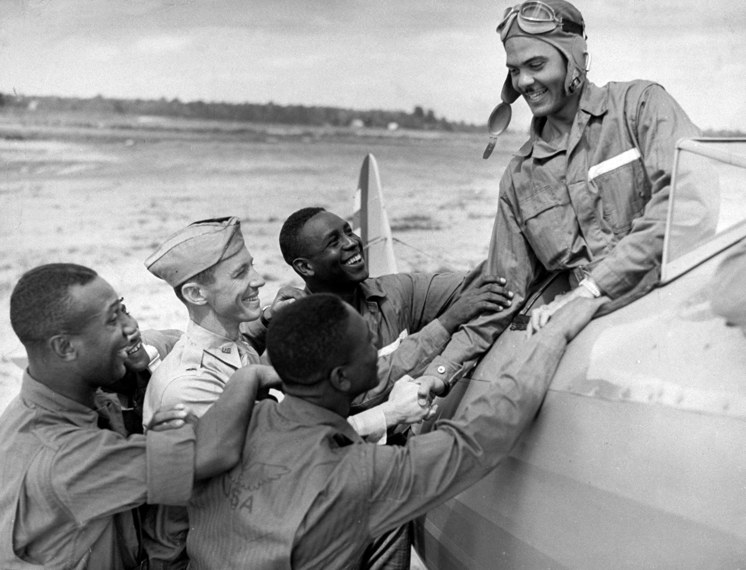 Captain Benjamin O. Davis Jr., of US Army Air Corps 99th Pursuit Squadron, in cockpit, greeted by other cadets at flight-training school, 1942.