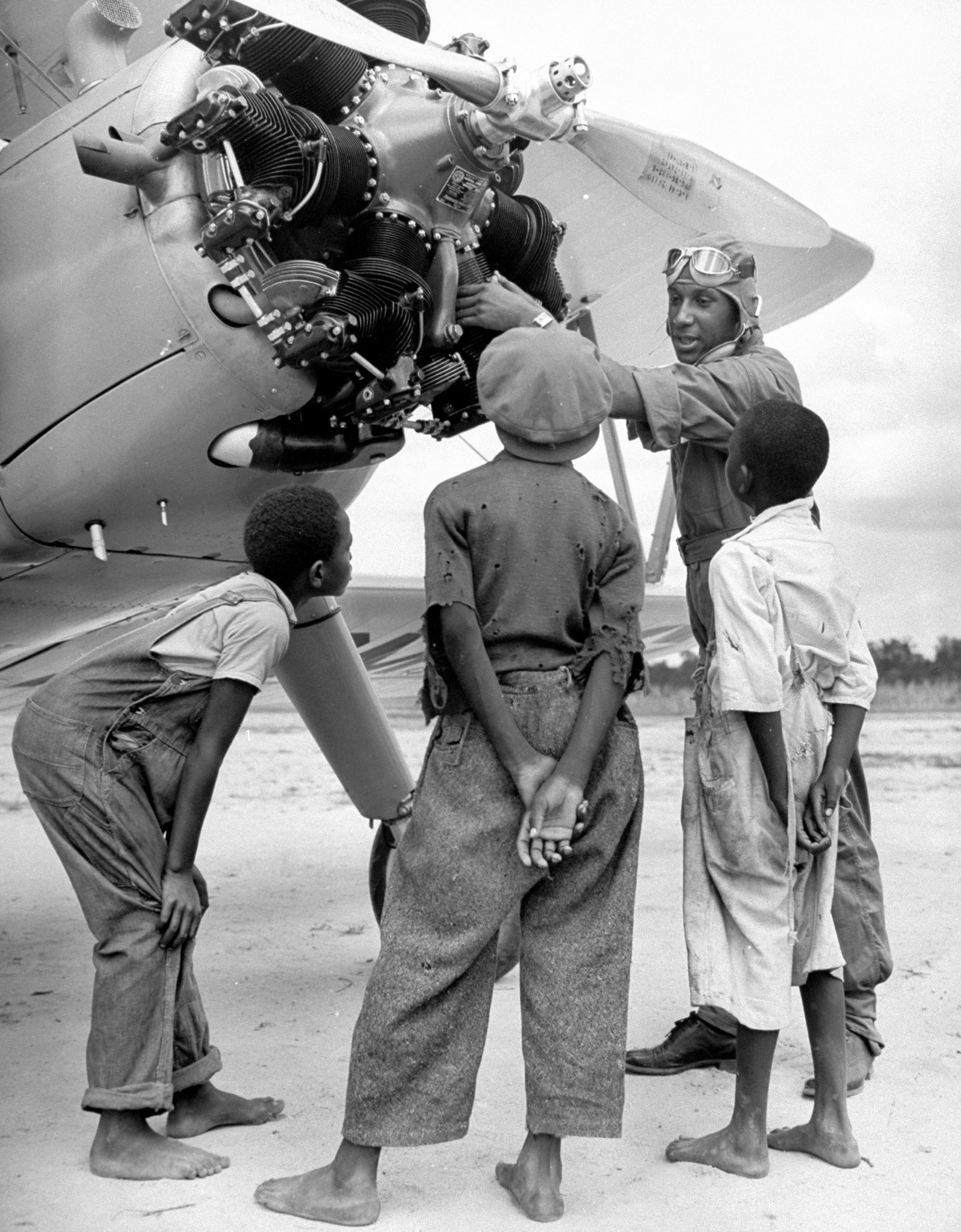 Cadet Custis, in training for US Army Air Corps 99th Pursuit Squadron, showing sharecropper's children aircraft engine on runway of flight school airfield, 1942.