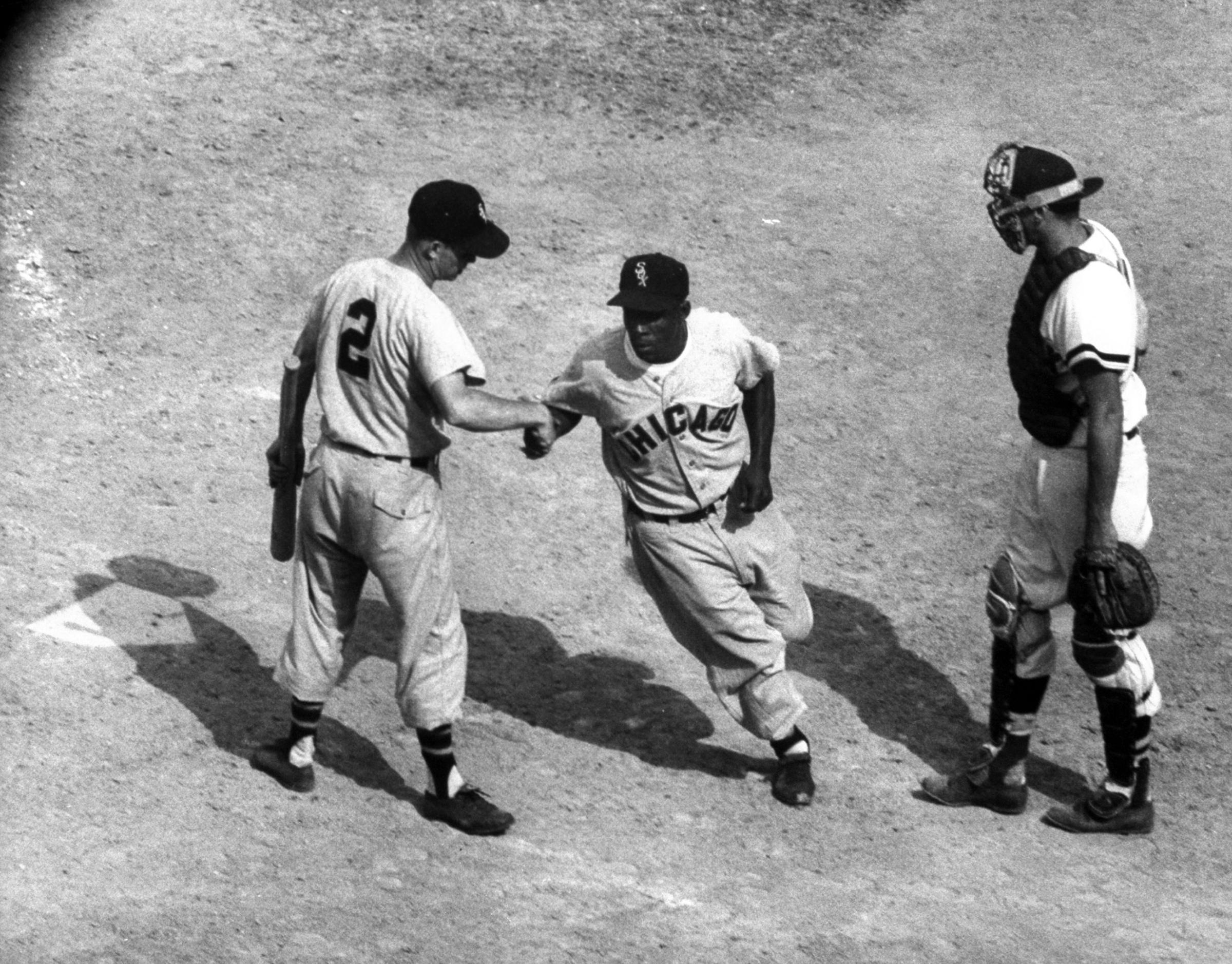 White Sox player, Nellie Fox, at home plate, shaking hands with Minnie Minoso, during game with Red Sox, 1959.
