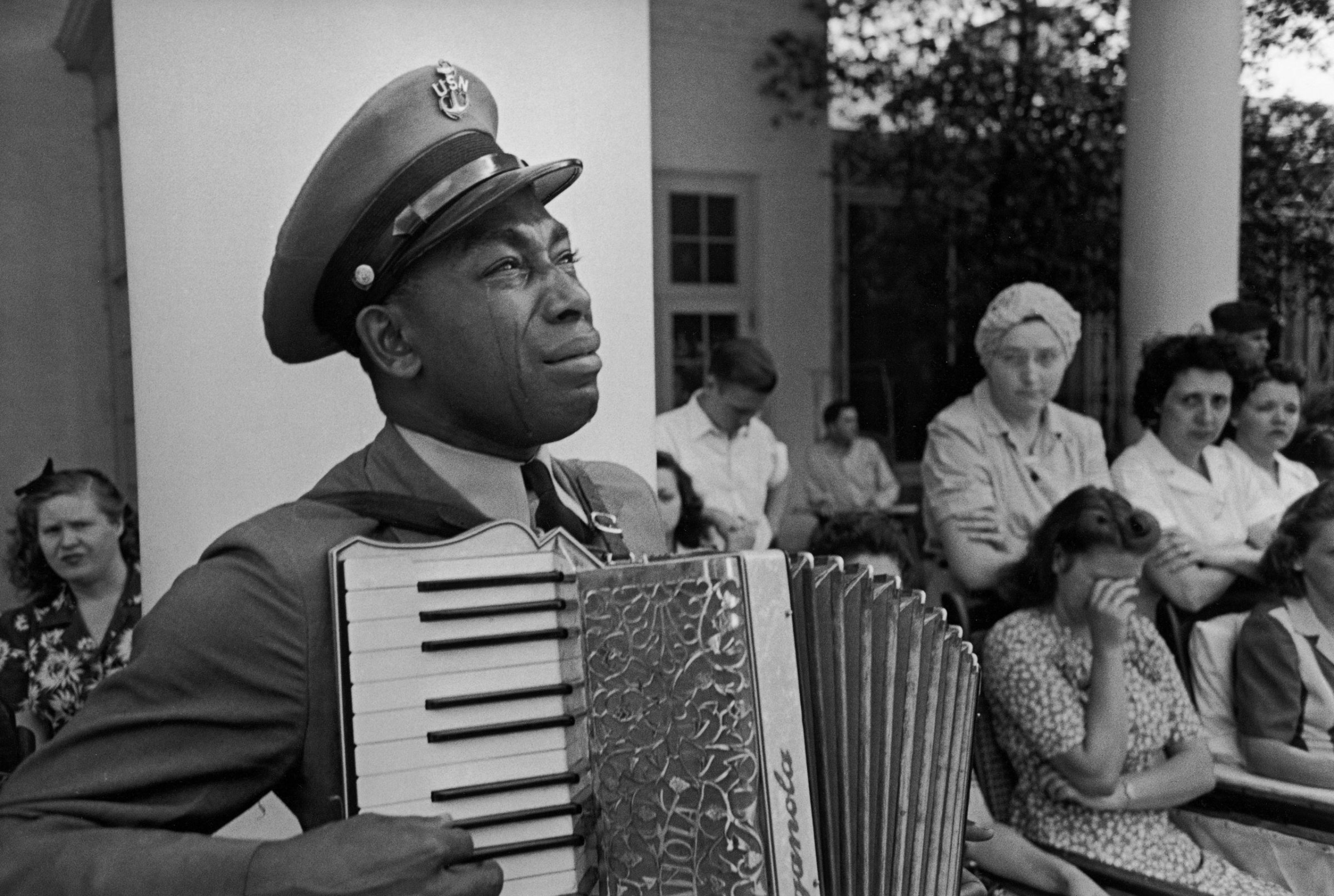 Tears stream down the cheeks of accordion-playing Chief Petty Officer (USN) Graham Jackson as President Franklin D. Roosevelt's flag-draped funeral train leaves Warm Springs, Ga., April 13, 1945.