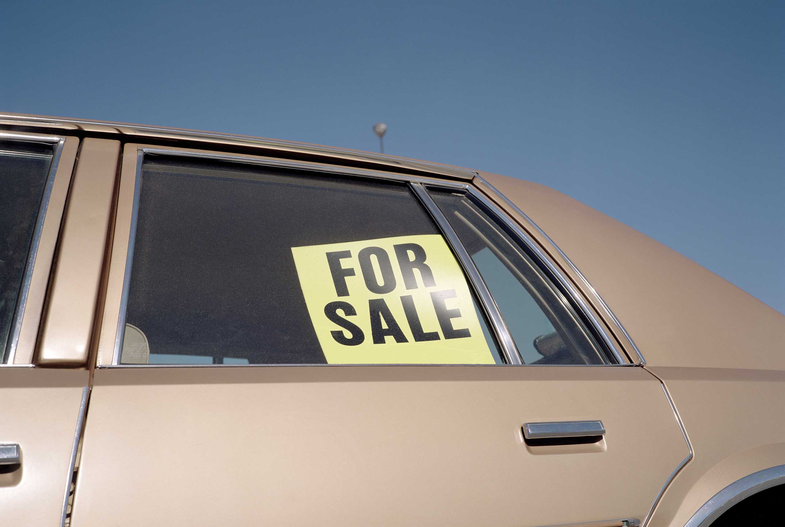 'For Sale' sign placed in car window, outdoors, close-up