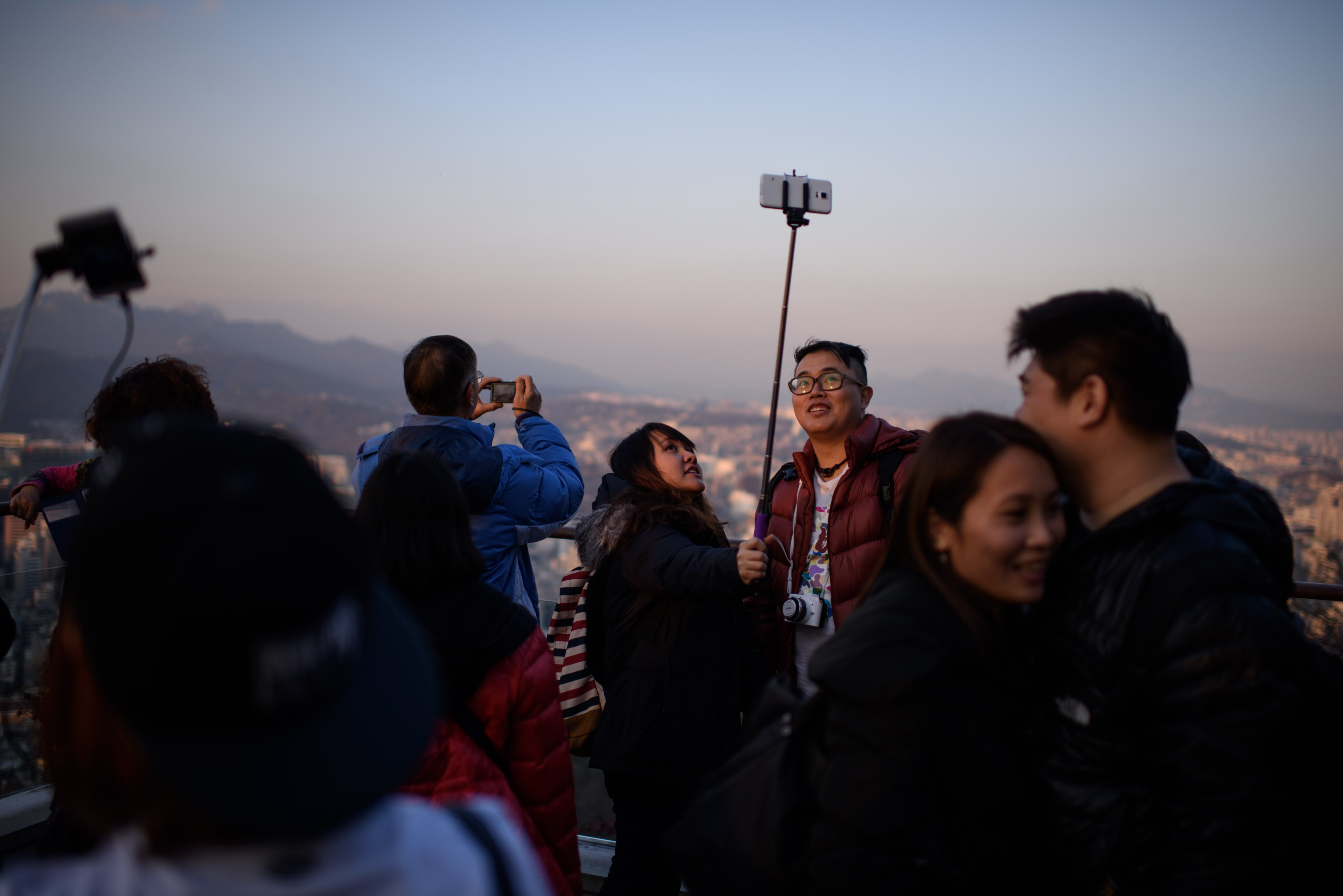 People use a 'selfie stick' to take a group photo overlooking the city skyline in Seoul, South Korea, on Nov. 26, 2014 (Ed Jones—AFP/Getty Images)