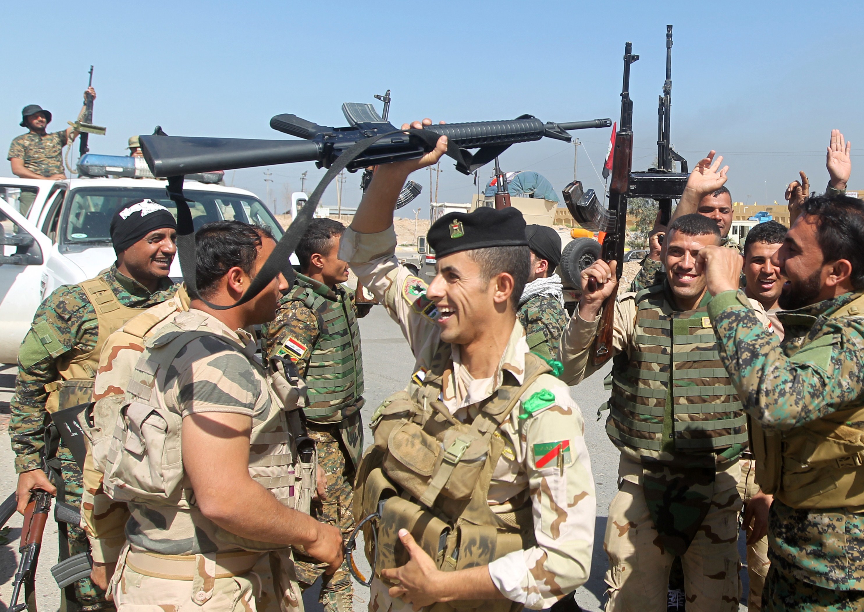 Iraqi soldiers raise their weapons as they cheer on the outskirts of the city of Tikrit as they prepare to launch a military operation to take control of the city from ISIS on March 10, 2015. (Ahmad al-Rubaye—AFP/Getty Images)