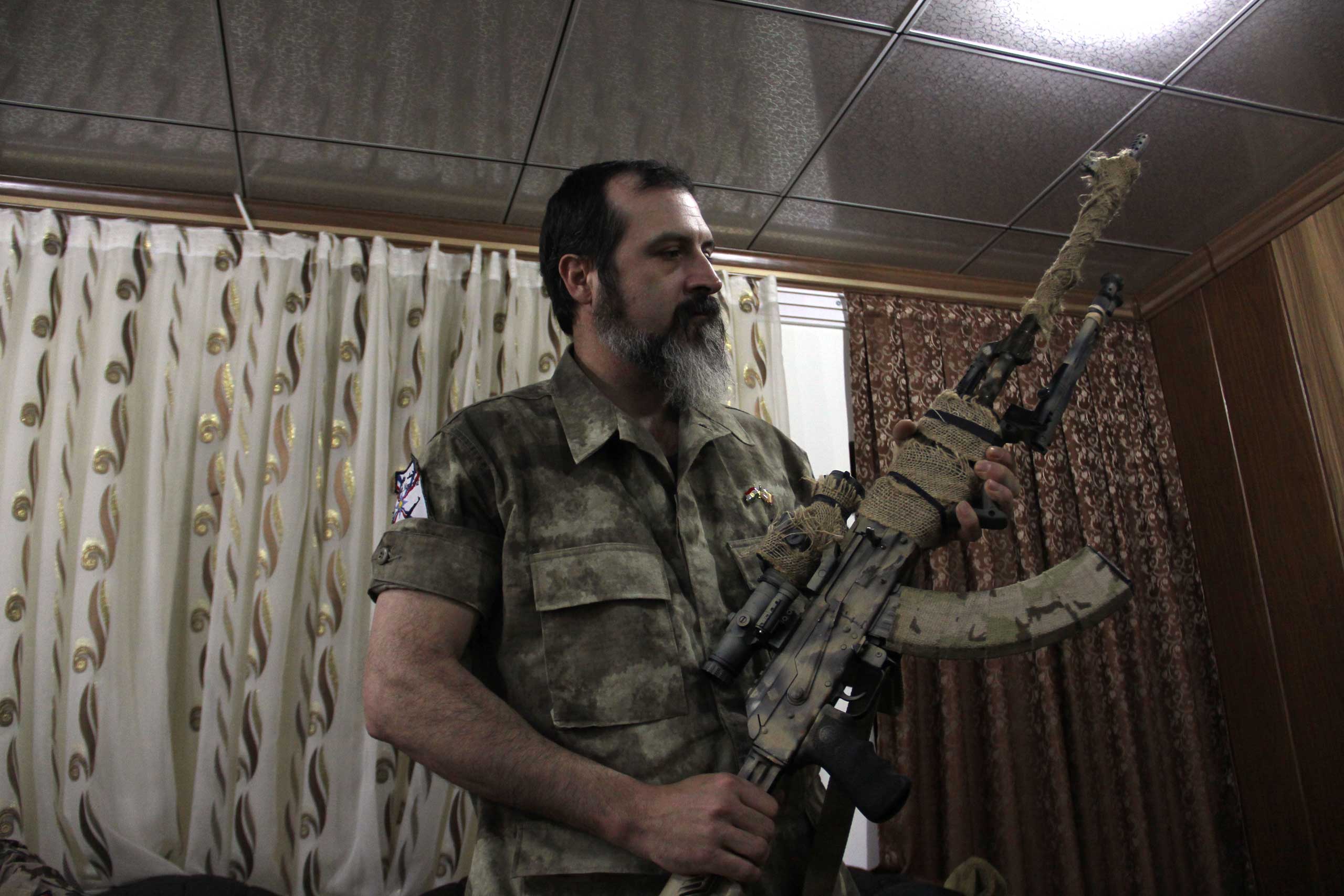 Scott holds his gun in the Dwekh Nawsha headquarters in Dohuk, northern Iraq. (Rebecca Collard)