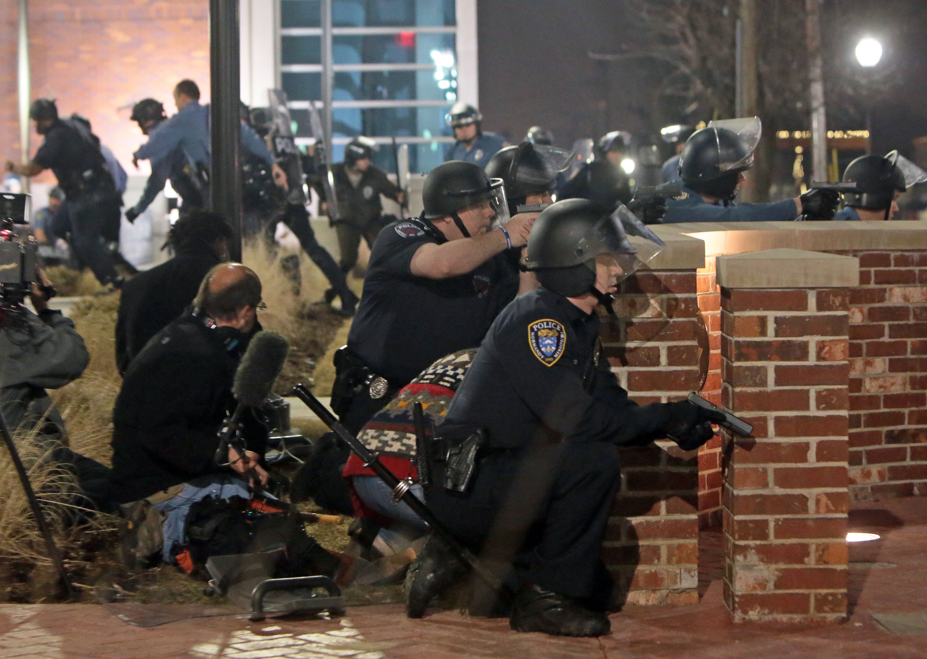 Police take cover after two officers were shot while standing guard in front of the Ferguson Police Station on Thursday, March 12, 2015.