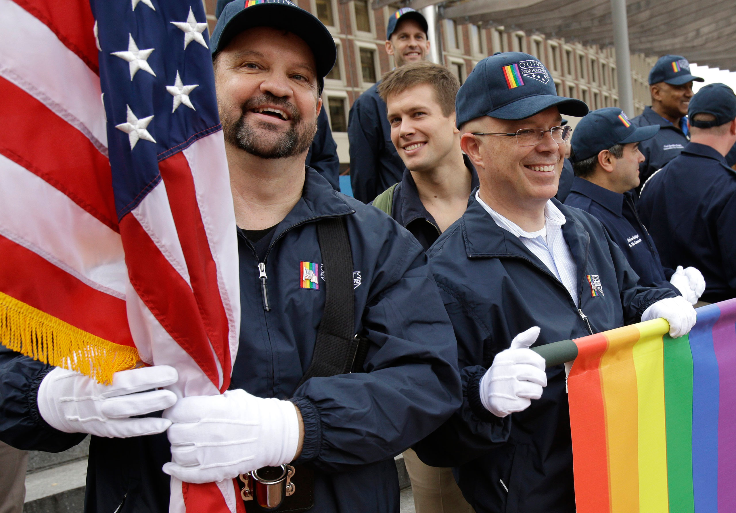 Retired U.S. Air Force Master Sgt. Eric Bullen, of Westborough, Mass., left, holds an American flag as U.S. Army veteran Ian Ryan, of Dennis, Mass., front right, rolls up an OutVets banner after marching with a group representing LGBT military veterans in a Veterans Day parade in Boston, Nov. 11, 2014. The organizers of Boston's annual St. Patrick's Day parade voted to allow the group of gay veterans along with a second group, Boston Pride, to march in this year's parade. (Steven Senne—AP)