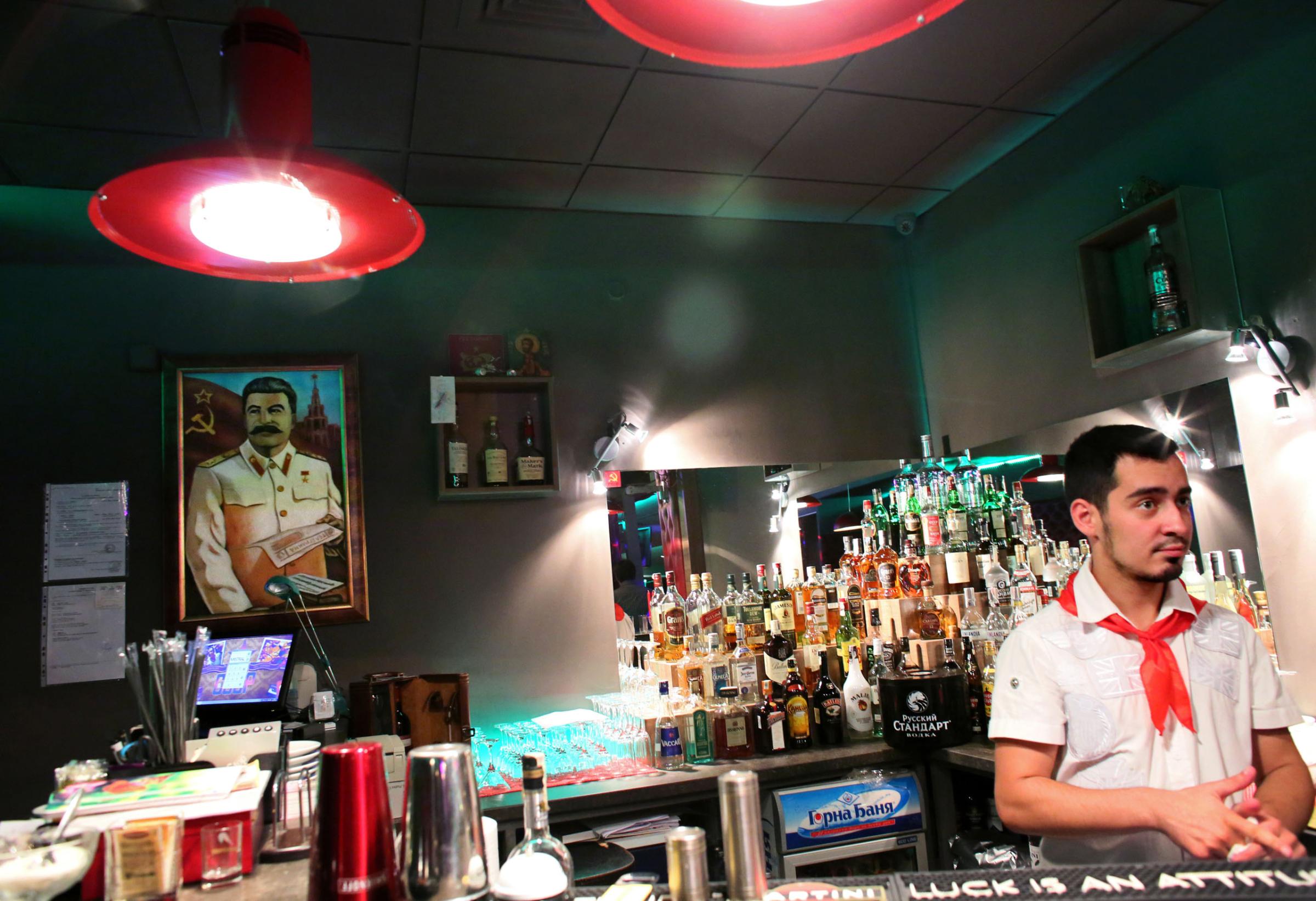 Kristiyan Stamatov serves drinks at SSSR, a USSR nostalgia restaurant and bar in Bulgaria's capital Sofia, in front of a portrait of Soviet communist leader Joseph Stalin, on October 4th, 2014. Stamatov is wearing a red tie, symbolic of what was once called a "pionerche" (pioneer,) or a Bulgarian student expected to serve the country and Communist party. This photo is from a project that aims to gauge the state and effect of democracy in the former Soviet satellite nation Bulgaria, two and a half decades after the fall of the Berlin Wall. The story of democracy in Bulgaria at age 25 is a cautionary tale about transplanting one-size-fits-all Western values to a nation still undergoing social and economic upheaval. Bulgaria is still one of the poorest, most corrupt nations in the European Union, its post-1989 hopes wilted by political instability, high crime rates and skyrocketing inflation. While Bulgarians can now freely vote and protest without much threat to their freedom, their new oppressor is corruption - which is at a 15 year high, across political and civil sectors alike. The ennui is so casually etched on the passerby's face that it becomes routine - one that fits in sadly well against a startling backdrop of rotting architecture, joblessness, and a vast population decline. Despite what democracy has changed in Bulgaria, the daily struggles of its populace remain largely untouched, trapped in a post-communist time capsule.This project was supported by a grant from The Pulitzer Center on Crisis Reporting. Photo by: Yana PaskovaCopyright © Yana Paskova 2014