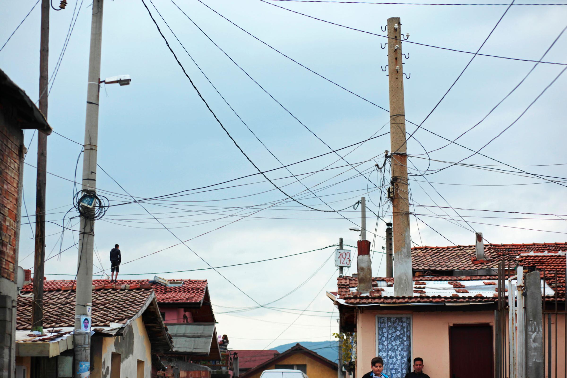 A man stands on a rooftop below a handmade electrical grid hanging over a Roma village, as people turn up to vote in October's Parliamentary elections in the nation's capital, Sofia. Today, October 5th, 2014, is also Midterm Elections day in the States - its multi-party ticket an unimaginable reality in autocratic Bulgaria pre-1989. Despite a month-long vacillation on the make-up of their political coalitions and their new prime minister - and that only 49% of the population turned up to vote today - party leaders narrowly avoided reelections, with former prime minister and leader of center-right party GERB Boyko Borisov reinstated at the post.This photo is from a project that aims to gauge the state and effect of democracy in the former Soviet satellite nation Bulgaria, two and a half decades after the fall of the Berlin Wall. The story of democracy in Bulgaria at age 25 is a cautionary tale about transplanting one-size-fits-all Western values to a nation still undergoing social and economic upheaval. Bulgaria is still one of the poorest, most corrupt nations in the European Union, its post-1989 hopes wilted by political instability, high crime rates and skyrocketing inflation. While Bulgarians can now freely vote and protest without much threat to their freedom, their new oppressor is corruption - which is at a 15 year high, across political and civil sectors alike. The ennui is so casually etched on the passerby's face that it becomes routine - one that fits in sadly well against a startling backdrop of rotting architecture, joblessness, and a vast population decline. Despite what democracy has changed in Bulgaria, the daily struggles of its populace remain largely untouched, trapped in a post-communist time capsule.This project was supported by a grant from The Pulitzer Center on Crisis Reporting. Photo by: Yana PaskovaCopyright © Yana Paskova 2014